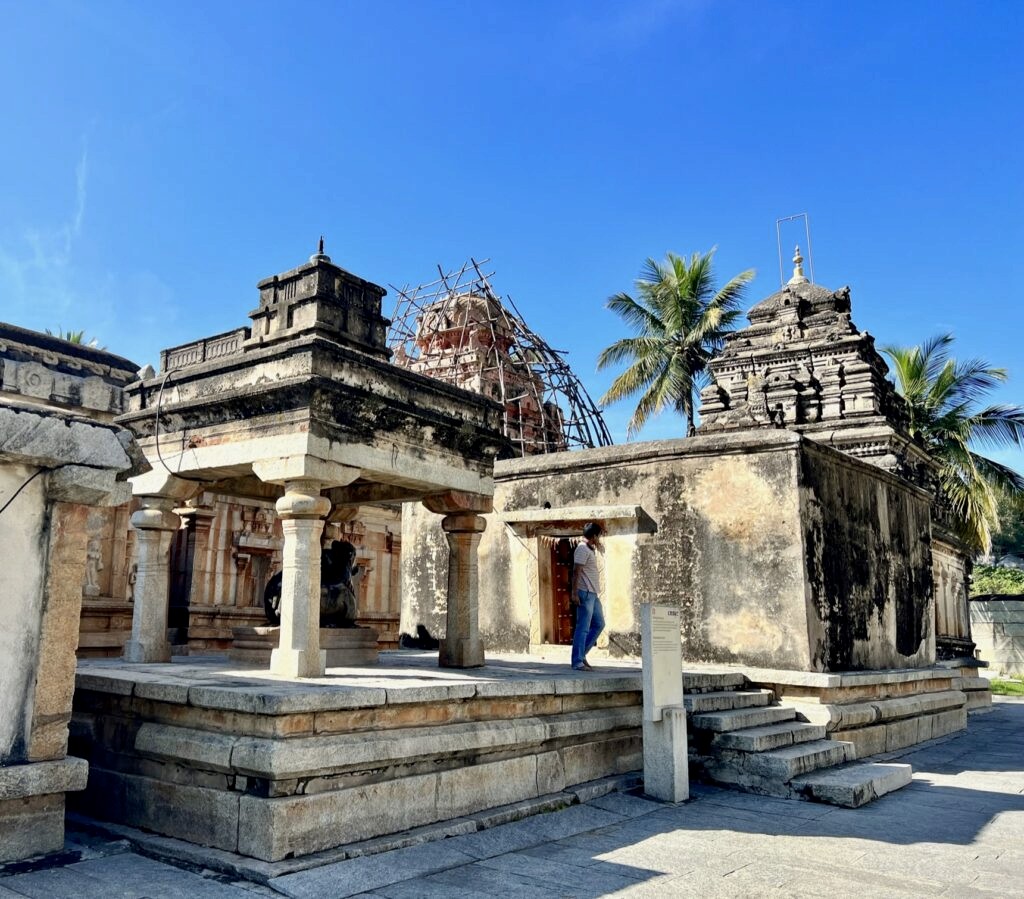 Nandi in an enclosure facing the Shiva linga. The temple is under renovation and a man is tanding on the platform on the temple.