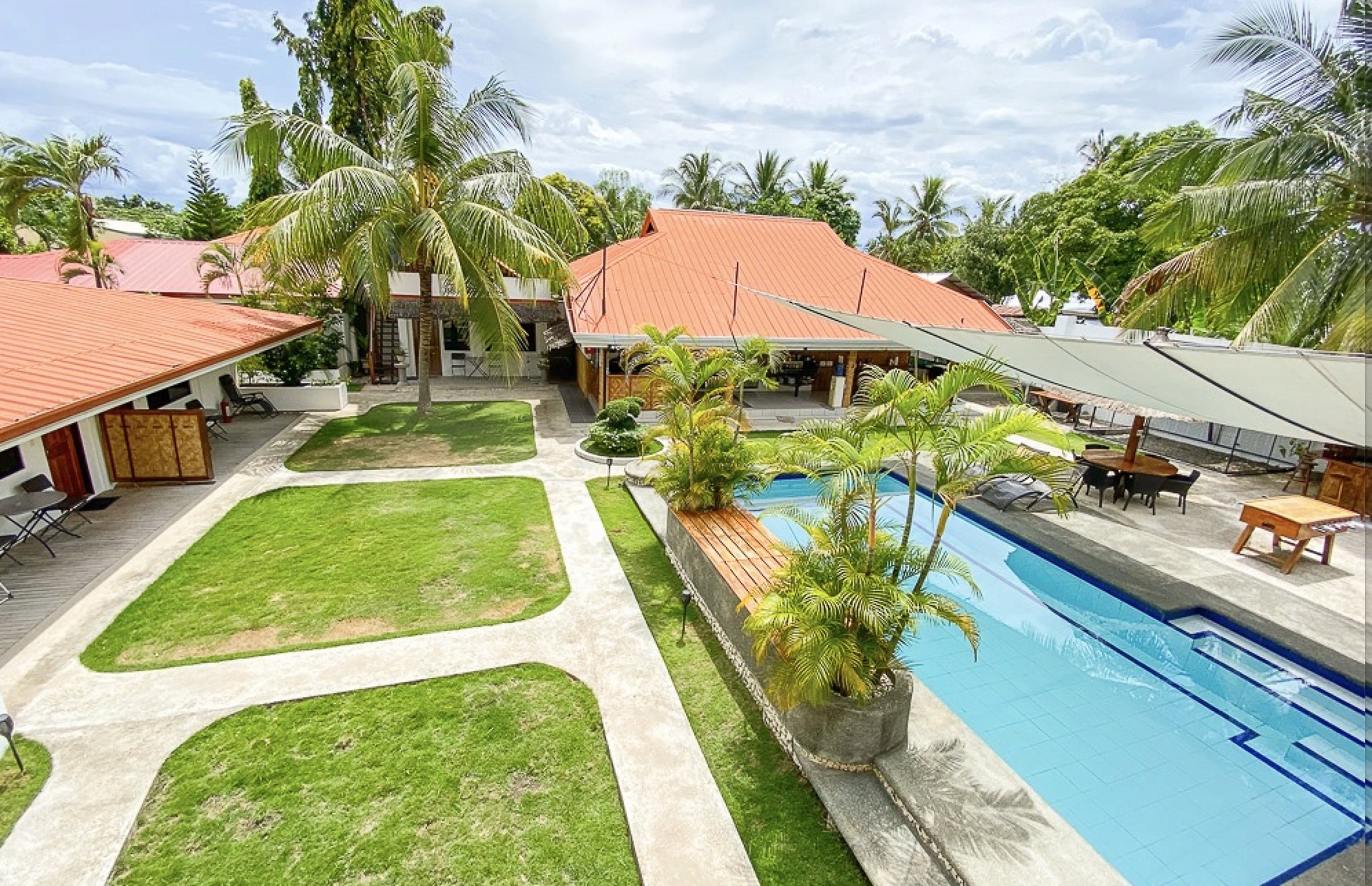Aerial view of a resort pool and orange-roofed buildings.