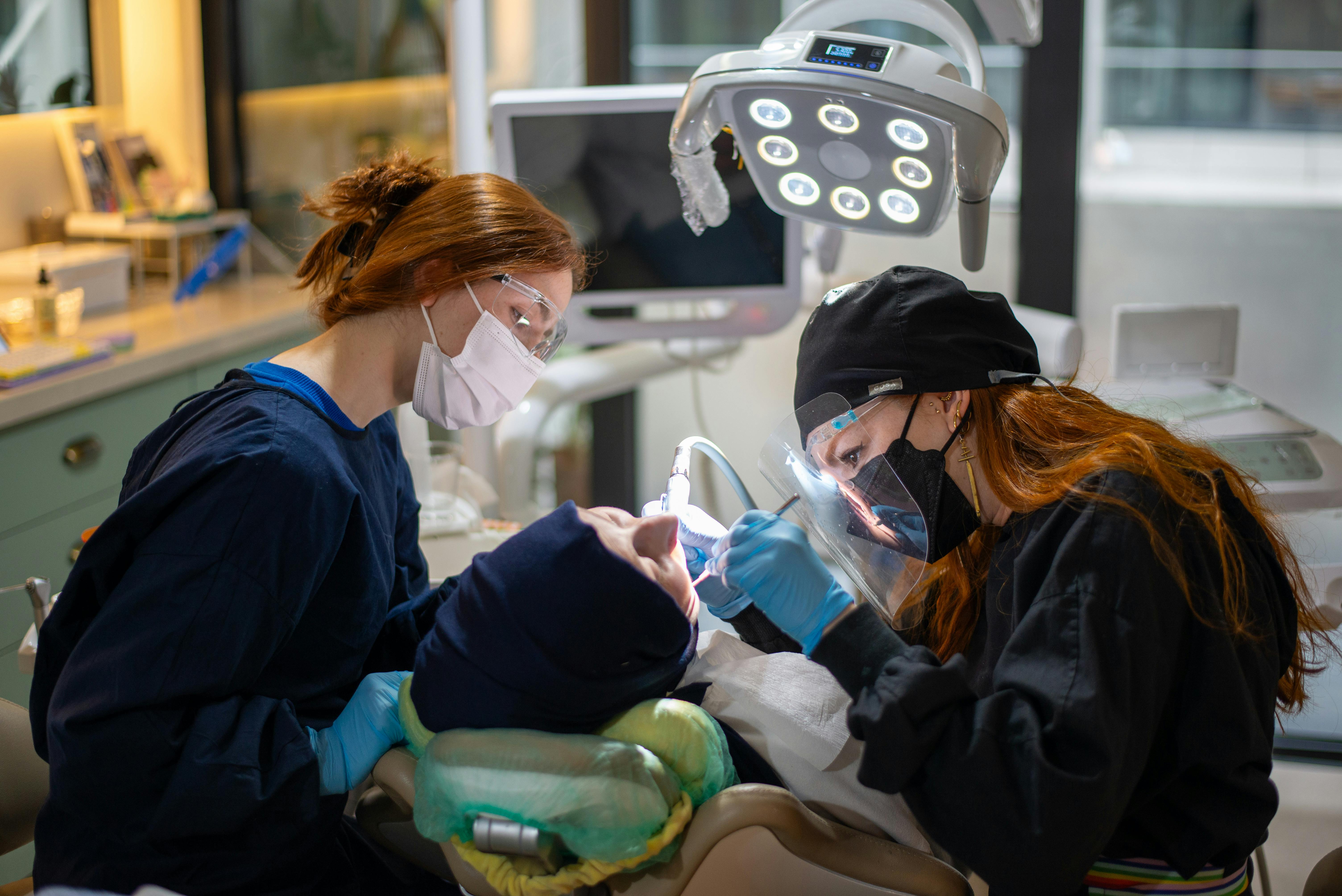 two hygienists working on a patient