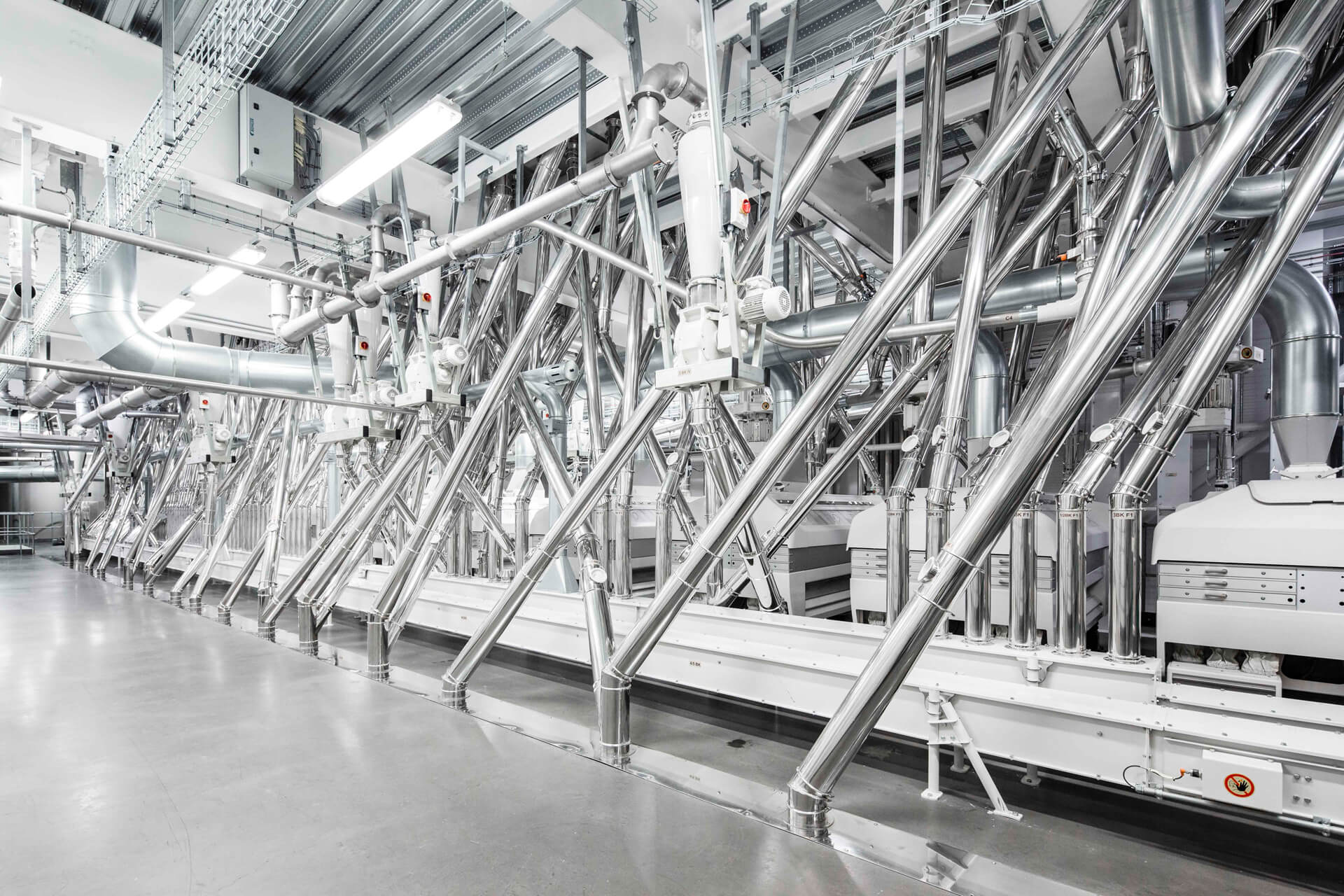 Industrial setting with white machinery and metal structures, reflecting light in a clean, spacious environment.