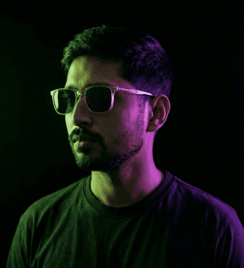 Portrait of Thiru N, Co-Founder and Creative Director, wearing sunglasses under neon purple and green lighting.