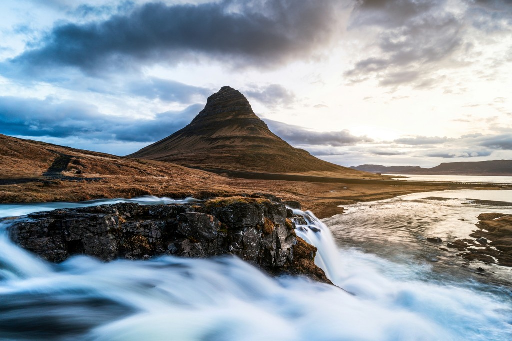 A waterfall with a brown mountain in the background