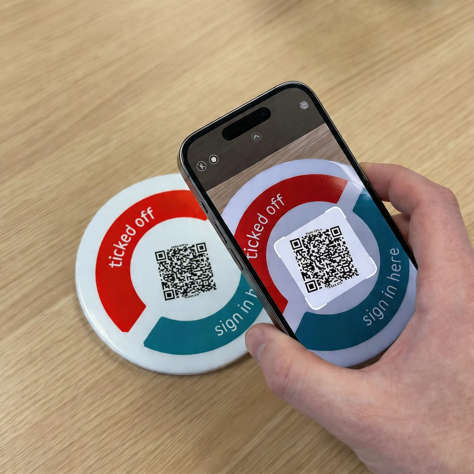 Image of someone scanning a QR token TickedOff positioned on the table.