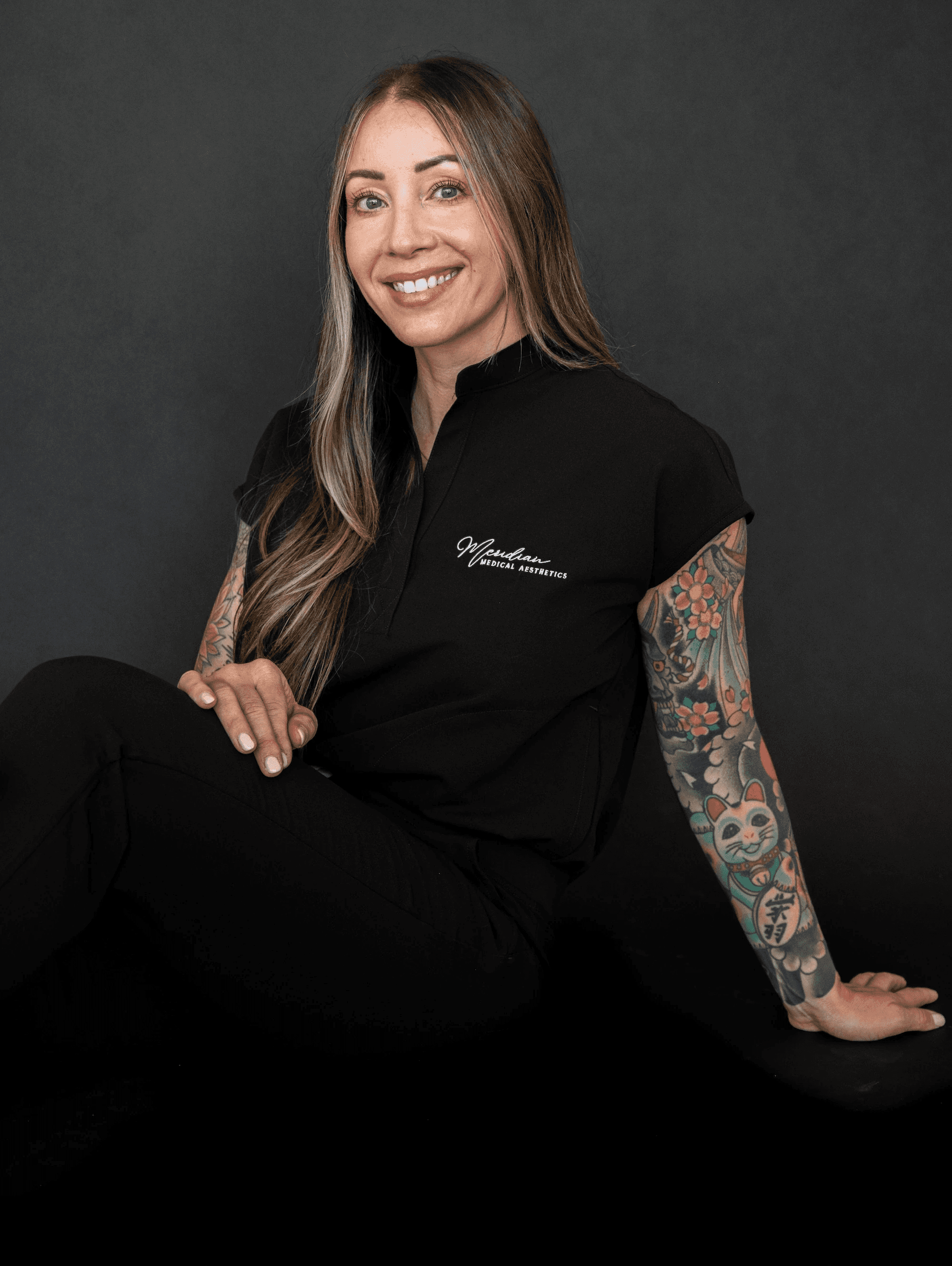 Portrait of licensed esthetician Matsuju Ward of Meridian Medical Aesthetics, smiling in professional uniform against a dark background.