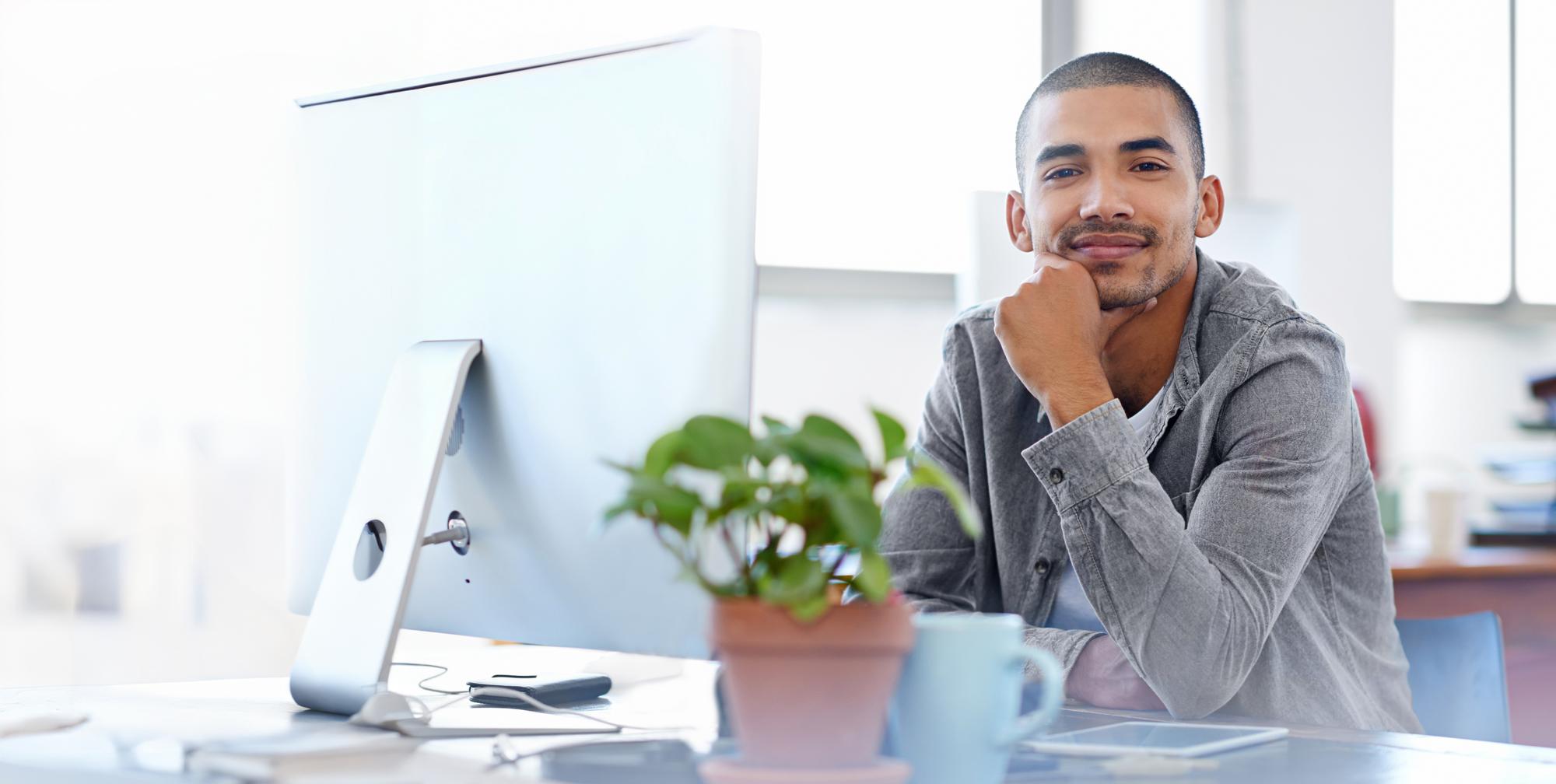 A man sits at his office computer and prepares to work