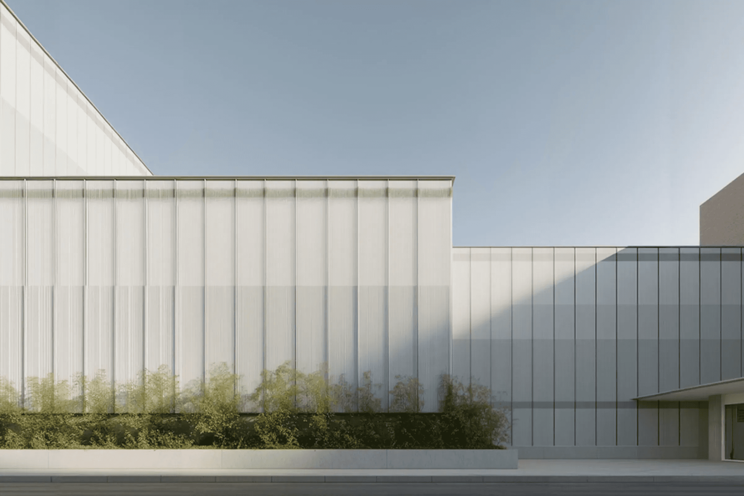 Modern minimalist building facade with vertical glass panels and clear sky
