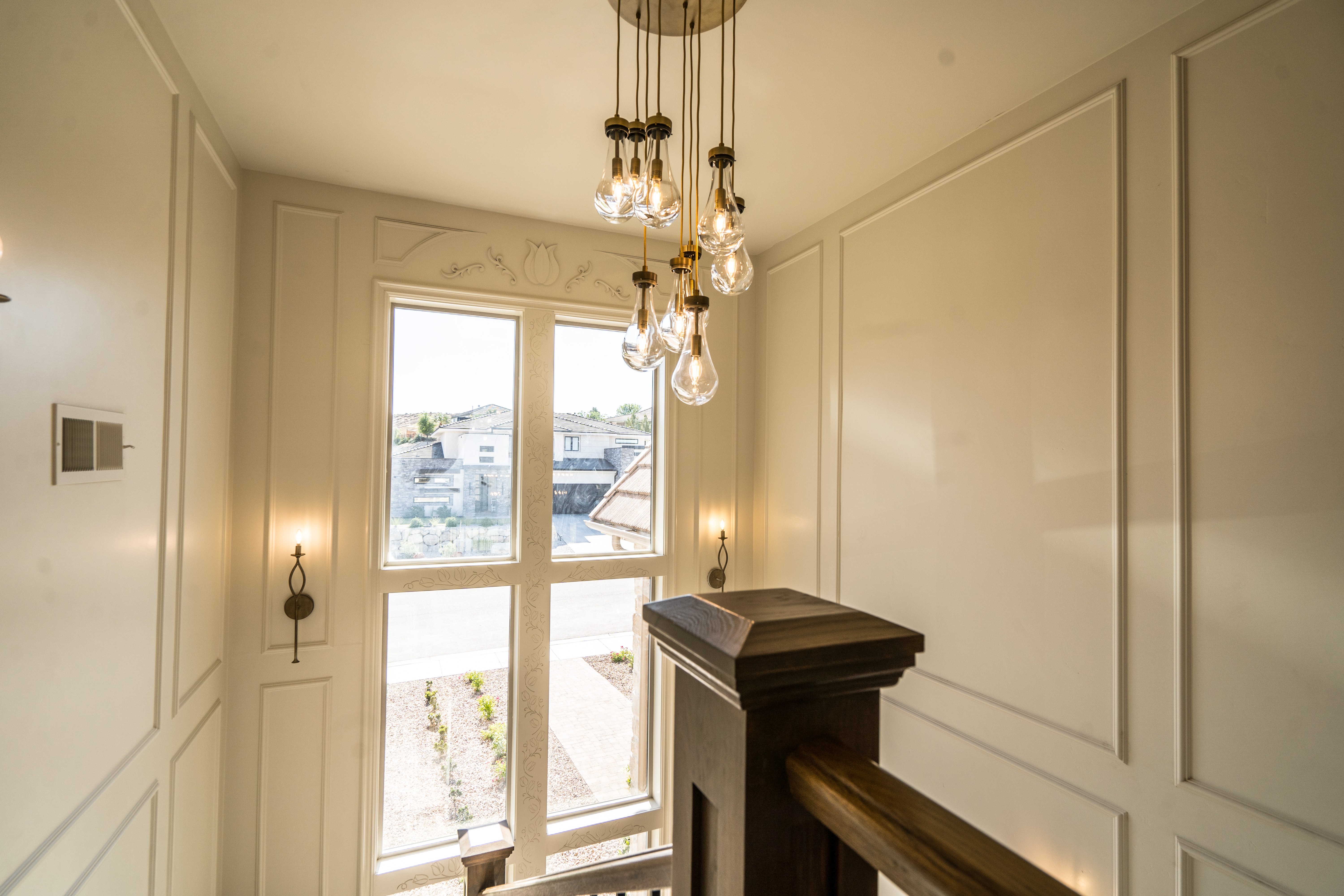 Staircase in a Washington, Utah custom home with a chandelier, wall molding, and detailed window casing.