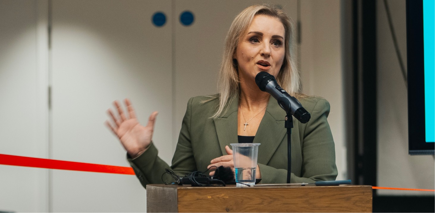 Person speaking at a podium with headphones and microphone.