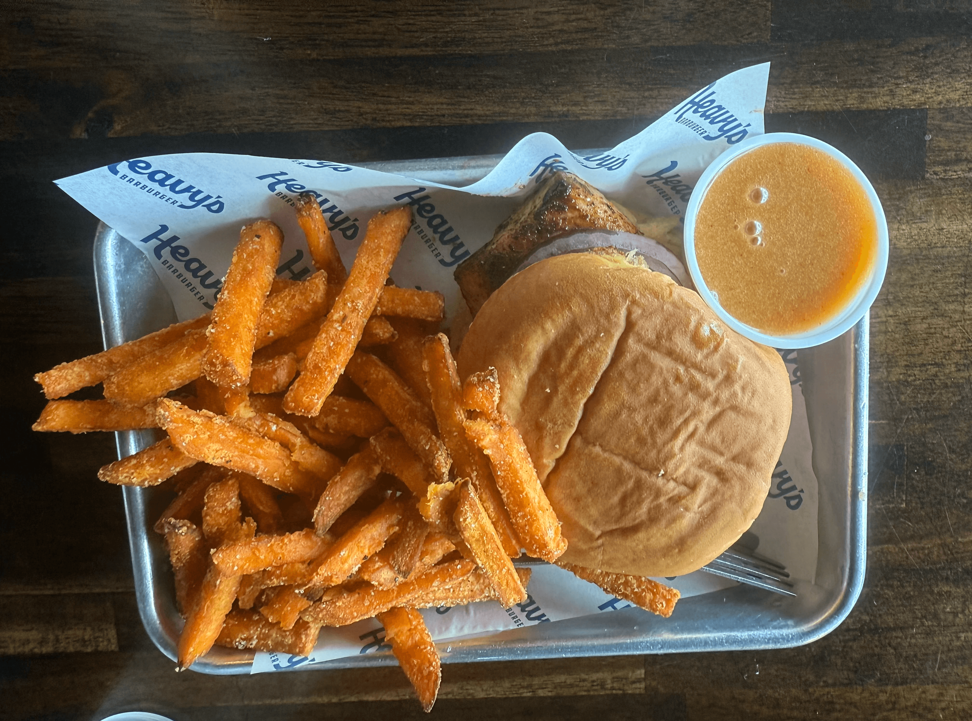 The St. Joe Blackened Mahi sandwich from Heavy’s Barburger, featuring seared mahi fillet with lettuce, tomato, red onion, and signature Heavy’s Sauce, served with crispy sweet potato fries.