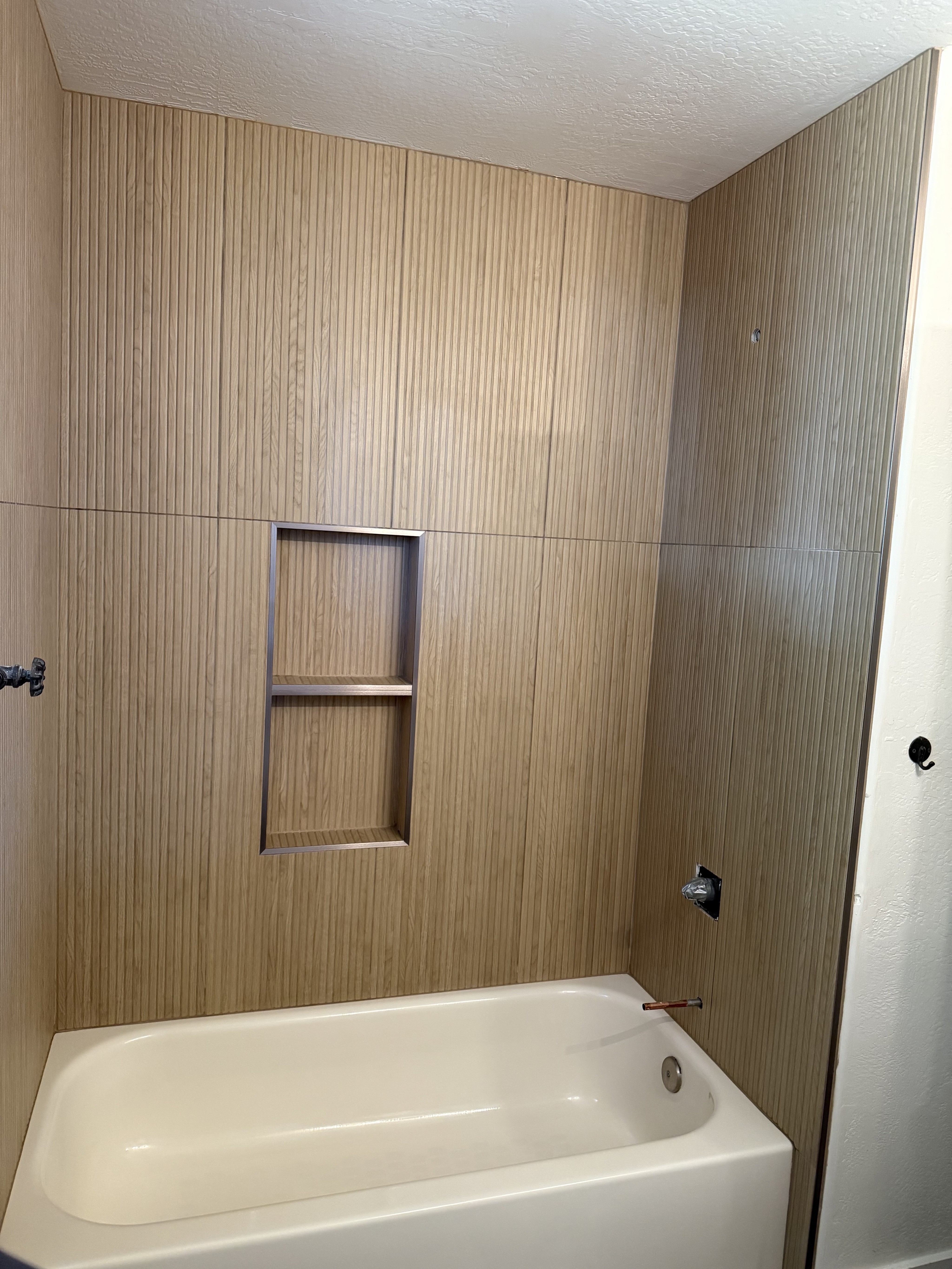 Spacious walk-in shower with clear glass enclosure and black fixtures, featuring white marble-look wall tiles and a white large format tile shower floor, part of a contemporary bathroom remodel.