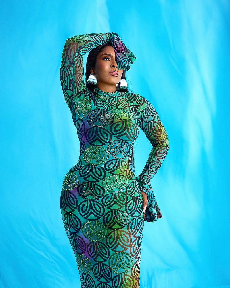 A person wearing a long sleeve, full-length dress with a multicolored geometric pattern.