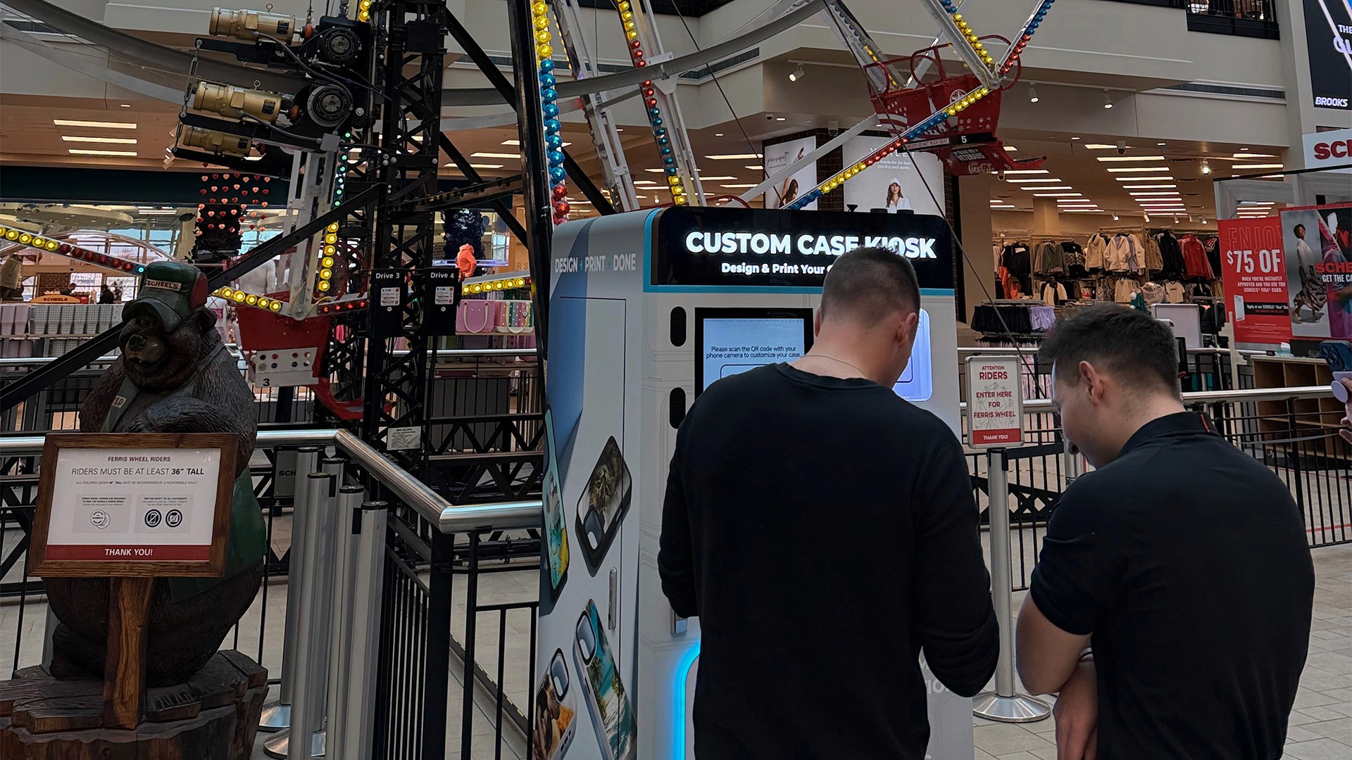 Custom Case Kiosk phone case printing machine in front of the indoor Ferris wheel at SCHEELS in Johnstown, Colorado.