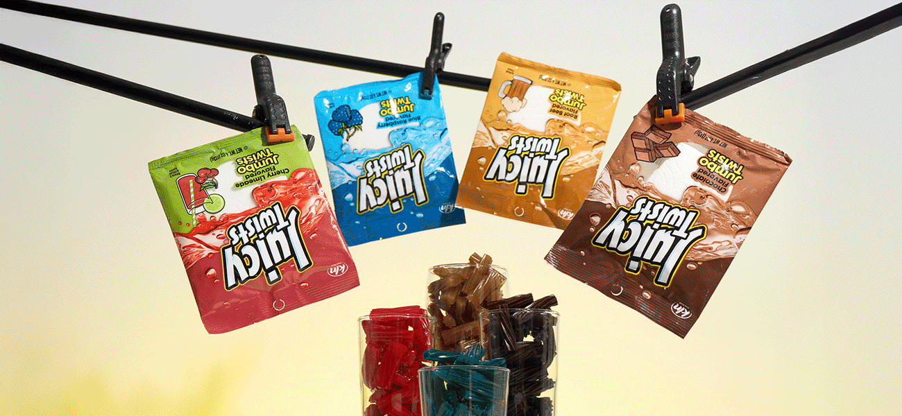 Assorted Juicy Twists candy pouches clipped to a hanging line, with clear containers of colorful candy pieces arranged below against a bright studio background.