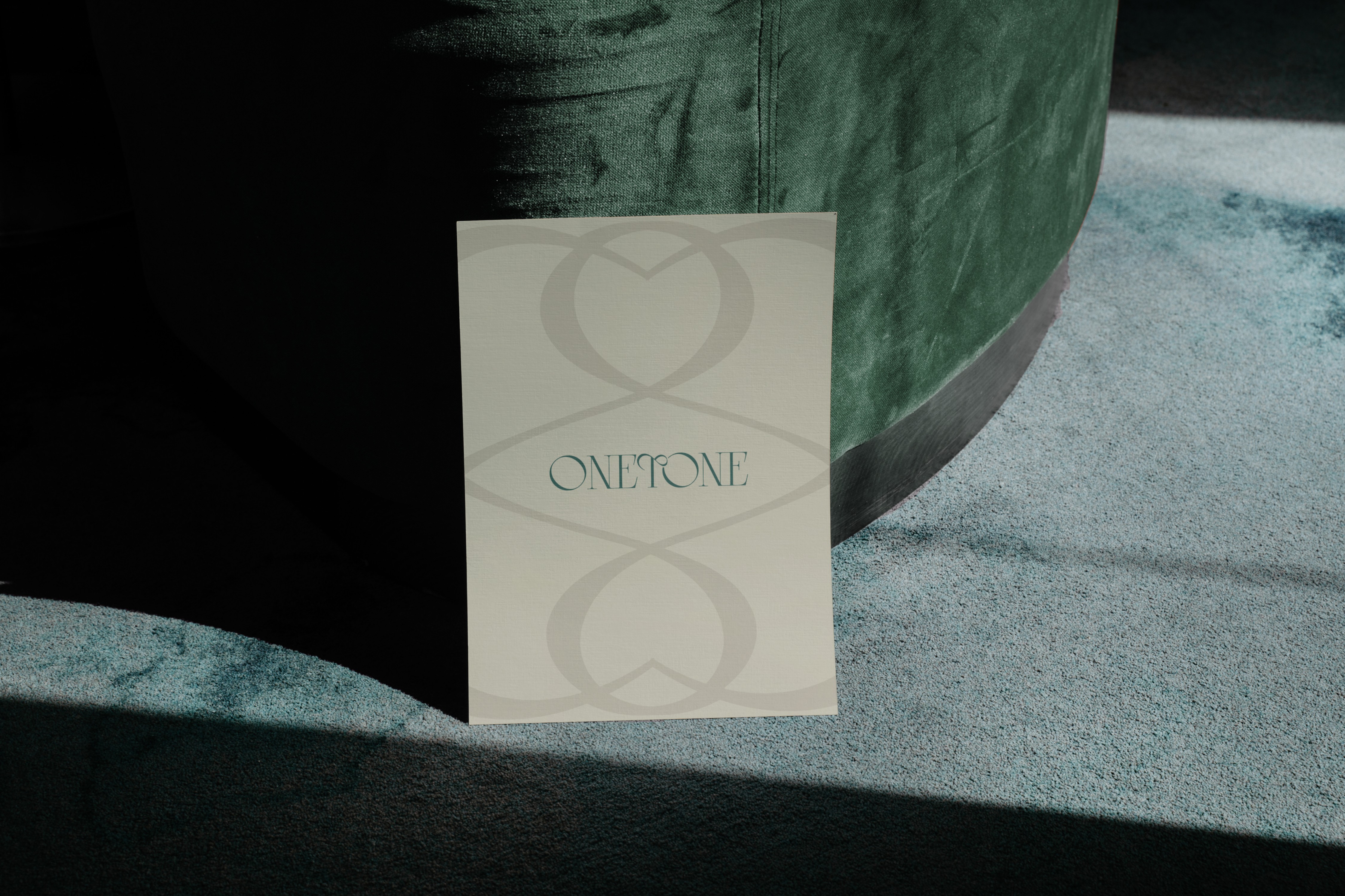 High-end fashion brand booklet – Onetone’s typography-focused print design, placed on a luxury velvet seat, exuding sophistication and exclusivity.