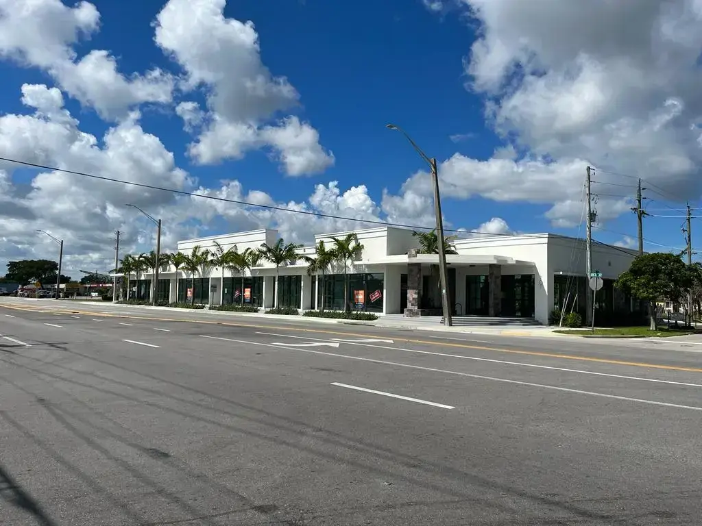 SPSA Retail Center front exterior with glass storefronts, palm trees, and stone columns along a Fort Lauderdale street