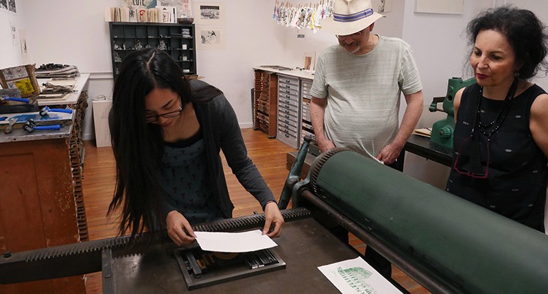 Student adjusting the paper on a pressing bench to make an imprint.