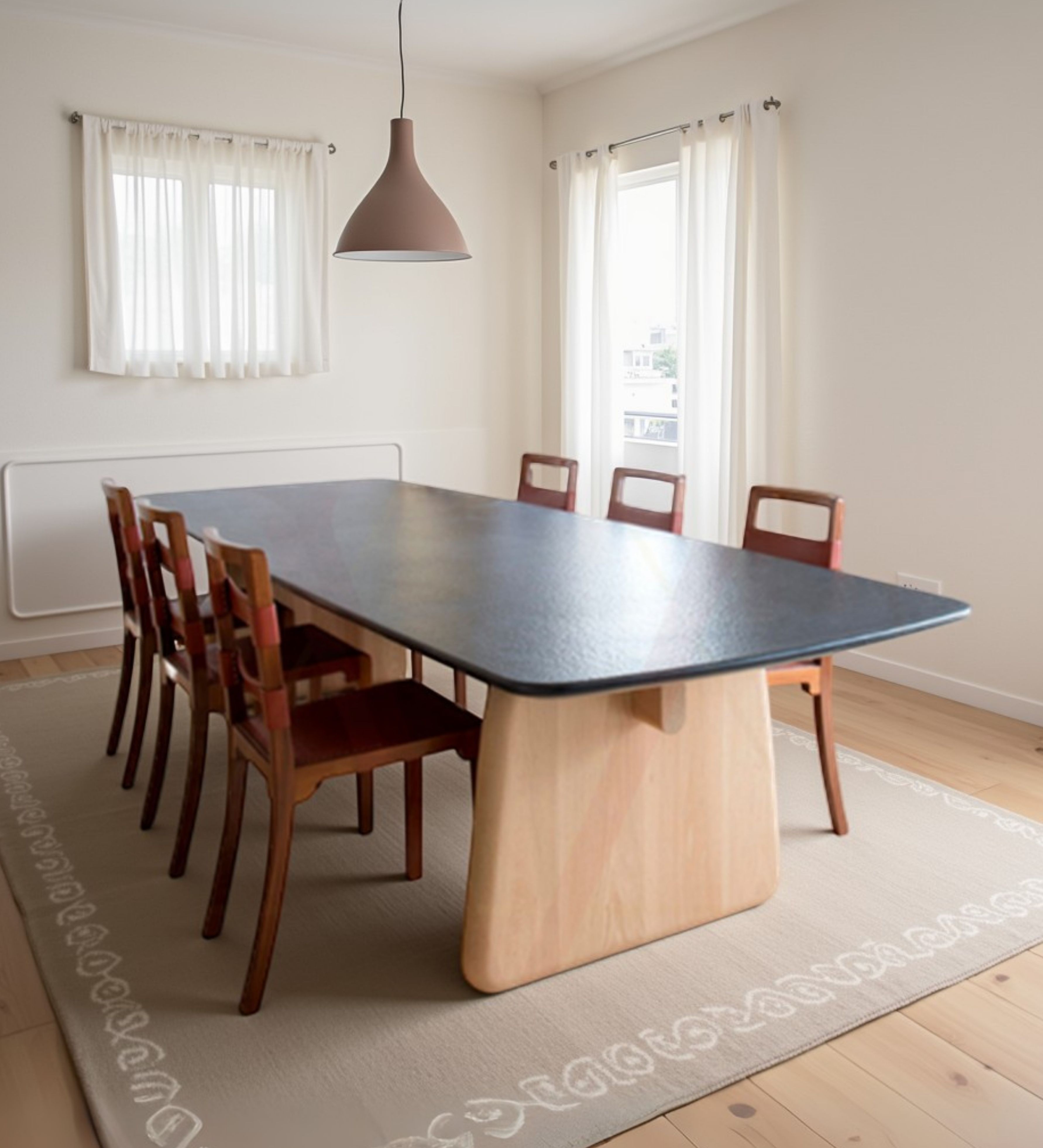 Modern styled dining table with thick central pedestal and dark tabletop, paired with straight wooden chairs