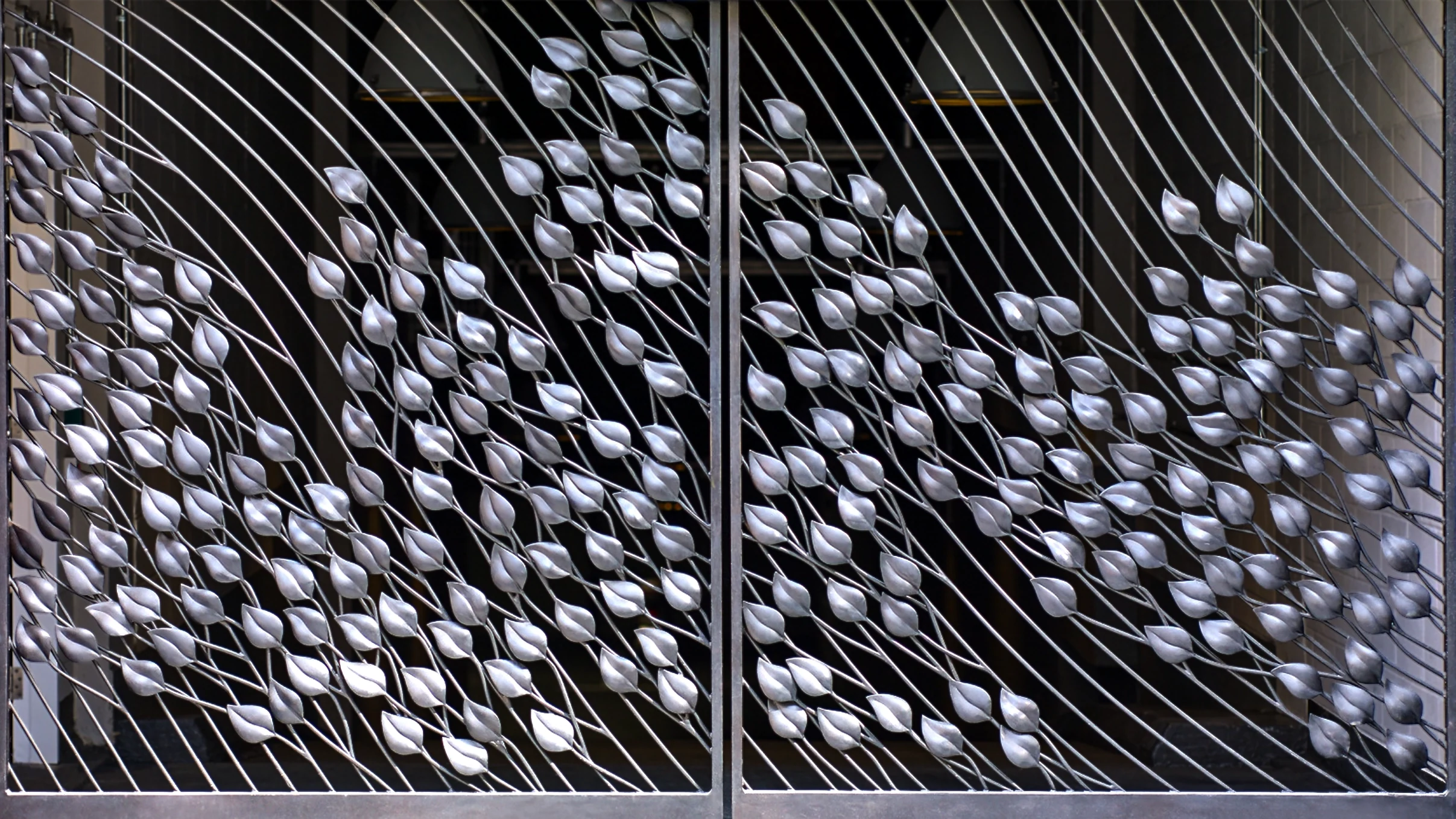 A large-scale architectural metal gate featuring a fluid pattern of silver, metallic hand-forged leaves climbing up diagonal bars. An architectural objet d’art installation designed by Shaun Leane for his new independent design studio.