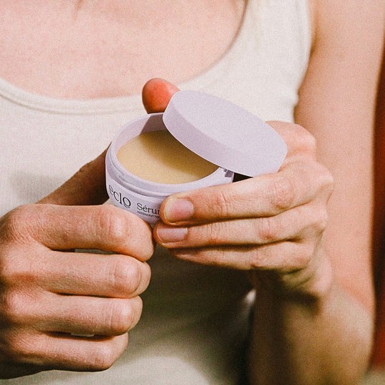 A model holding Éclo Sérum Lèvres Régénérant with hyaluronic acid in 15ml VIVOMER tubs. This showcases the material's compatibility with active skincare ingredients in a compact sustainable format.