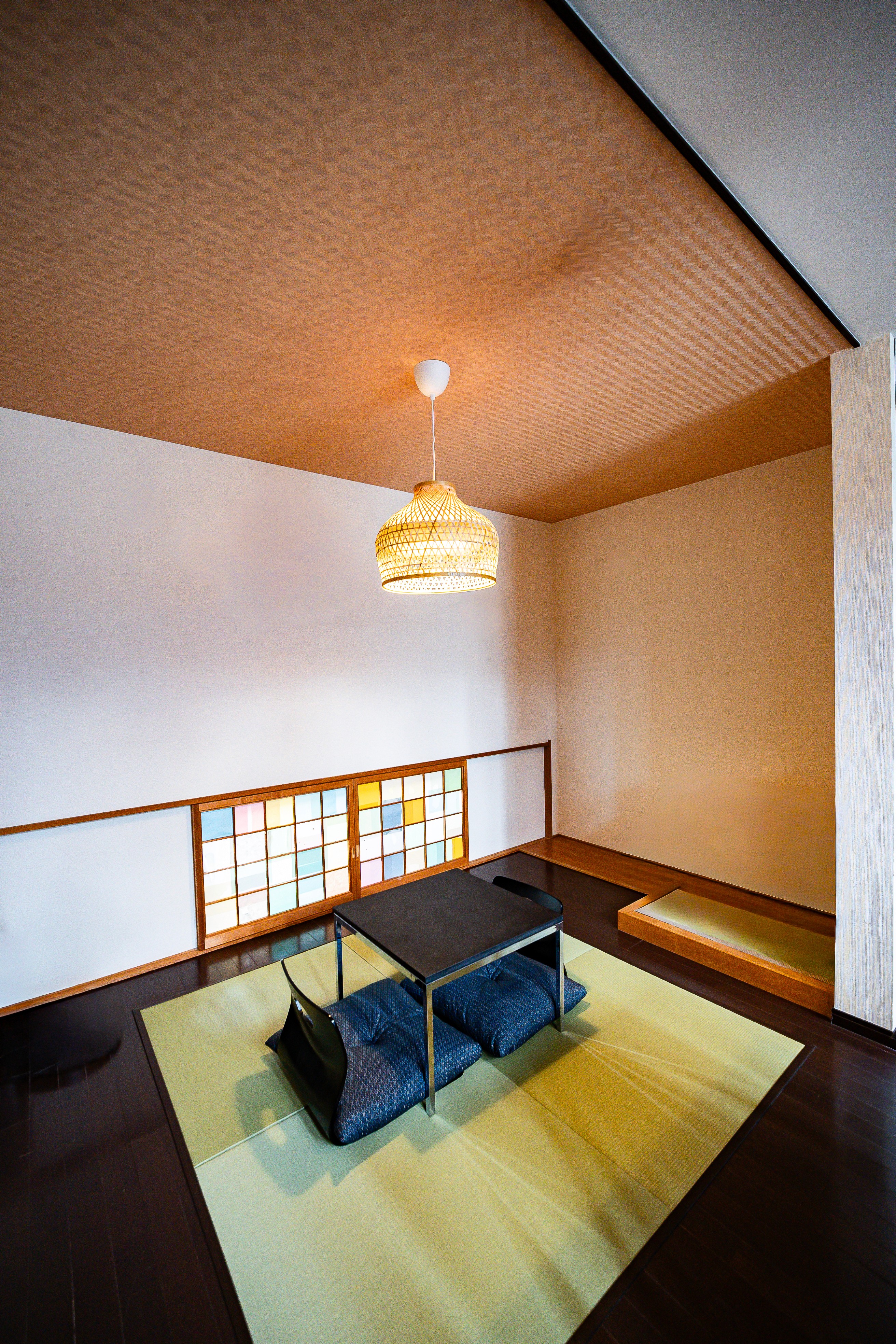A dining table in an open dining area with traditional decorative art pieces displayed on the wall behind.