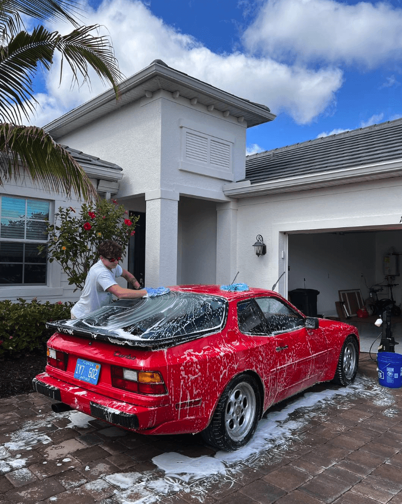 Gulfstream Mobile Detailing performing a thorough hand wash on a red sports car at a Florida home, highlighting expert mobile car detailing services in Naples and Fort Myers.