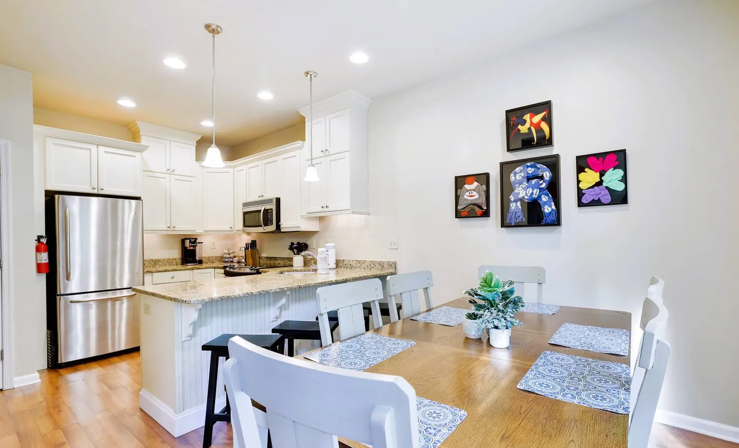 Dining table with white chairs beside the kitchen breakfast bar at Pop's Place