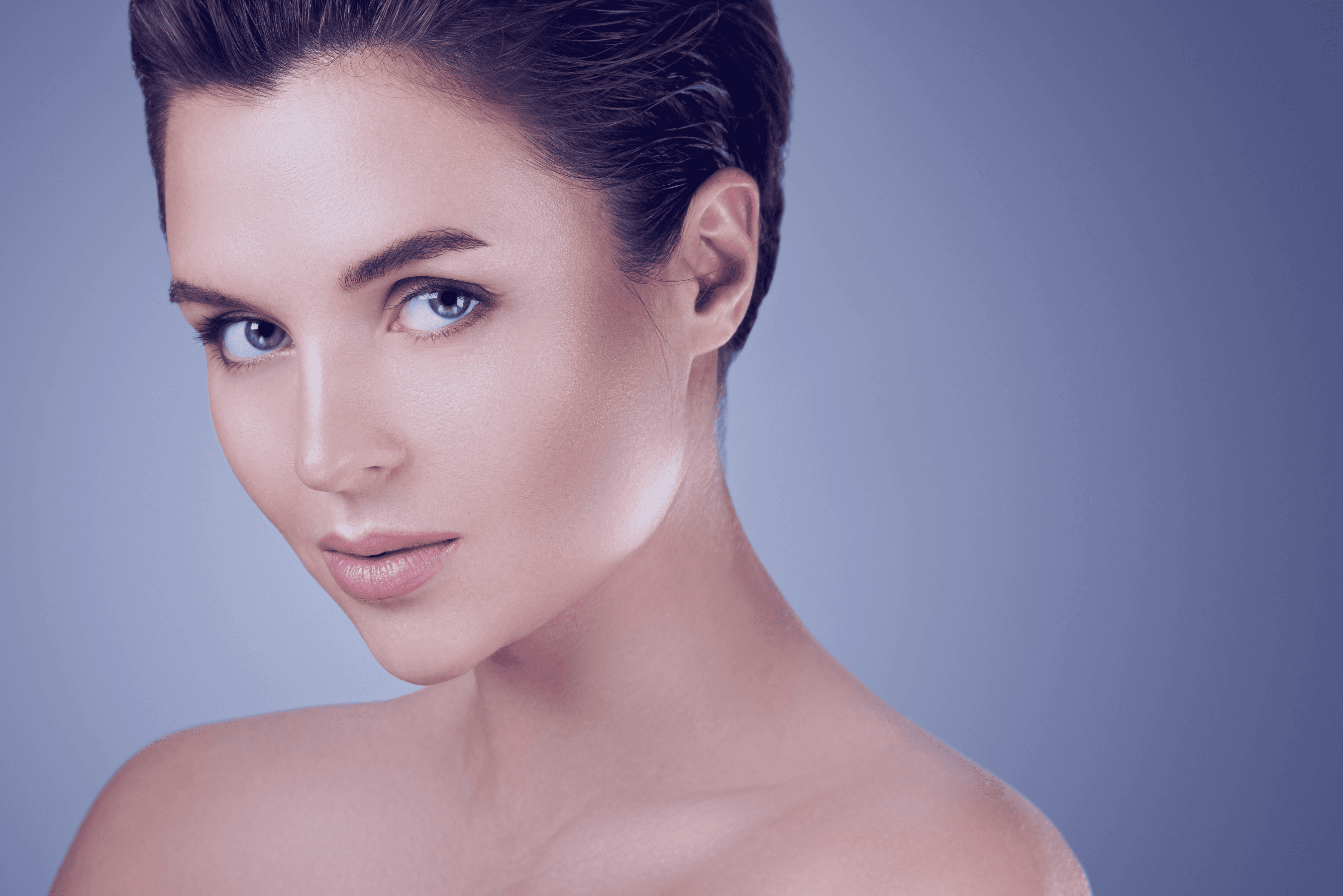 Woman with flawless skin and soft makeup against a gray background