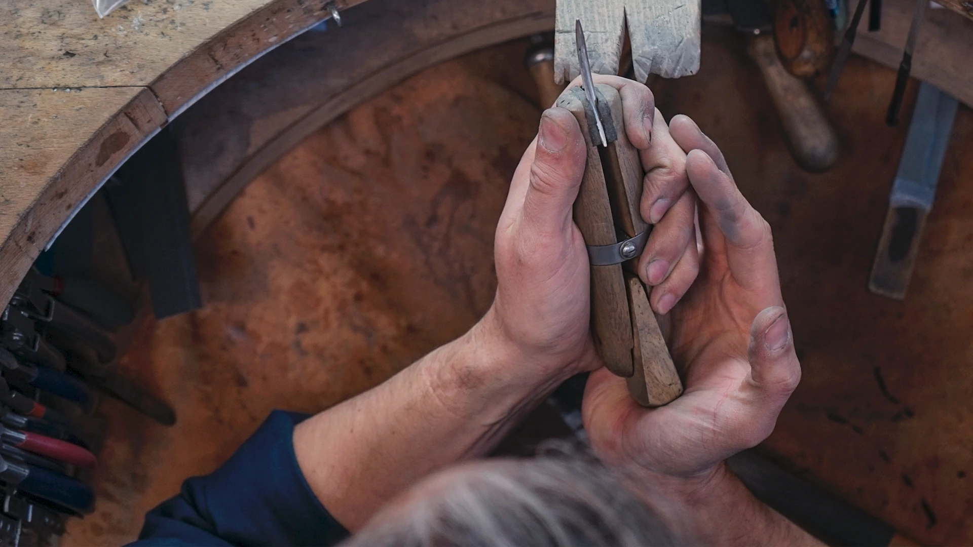 Silversmith shaping metal by hand at the bench for a 12 creation