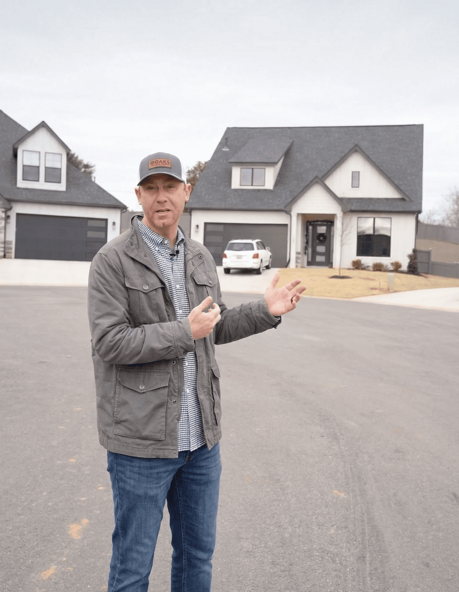 A smiling young man with crossed arms, wearing a plaid shirt and white t-shirt, poses against a dark background.
