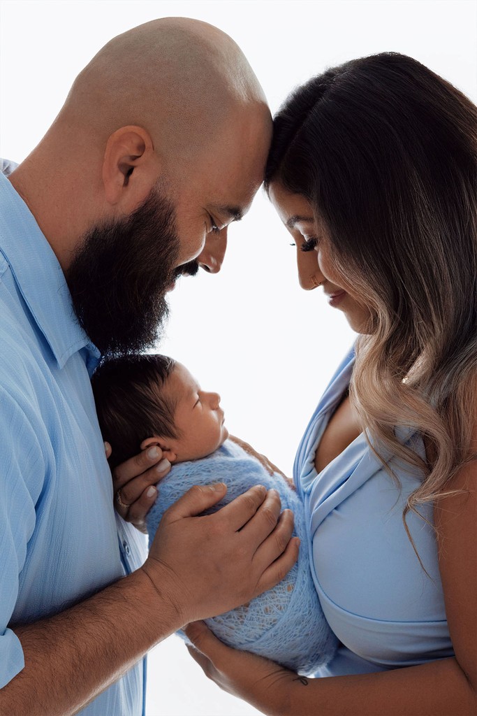 Tender family moment — parents holding their newborn baby during studio session.