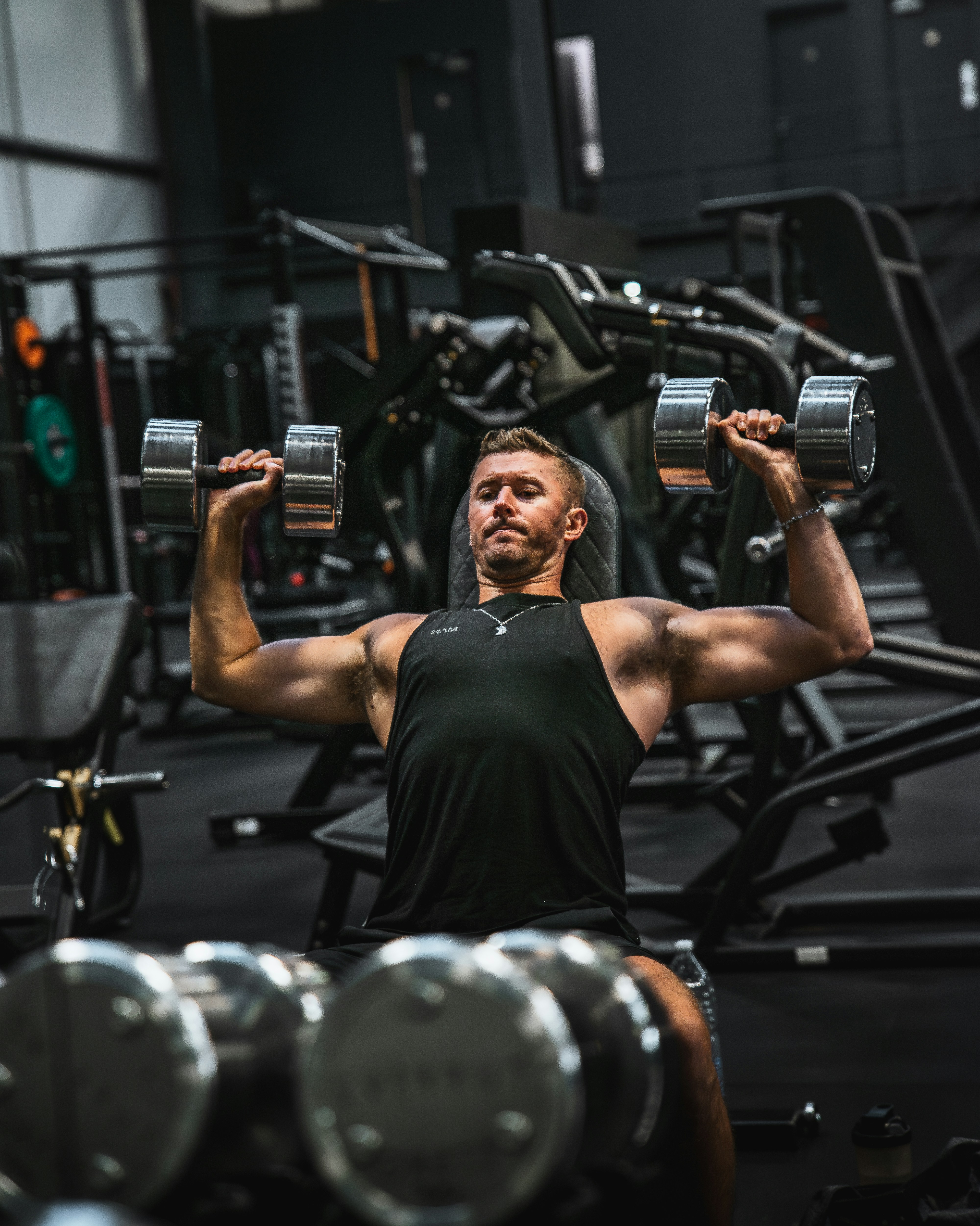 Man performing a dumbbell chest press exercise in a gym