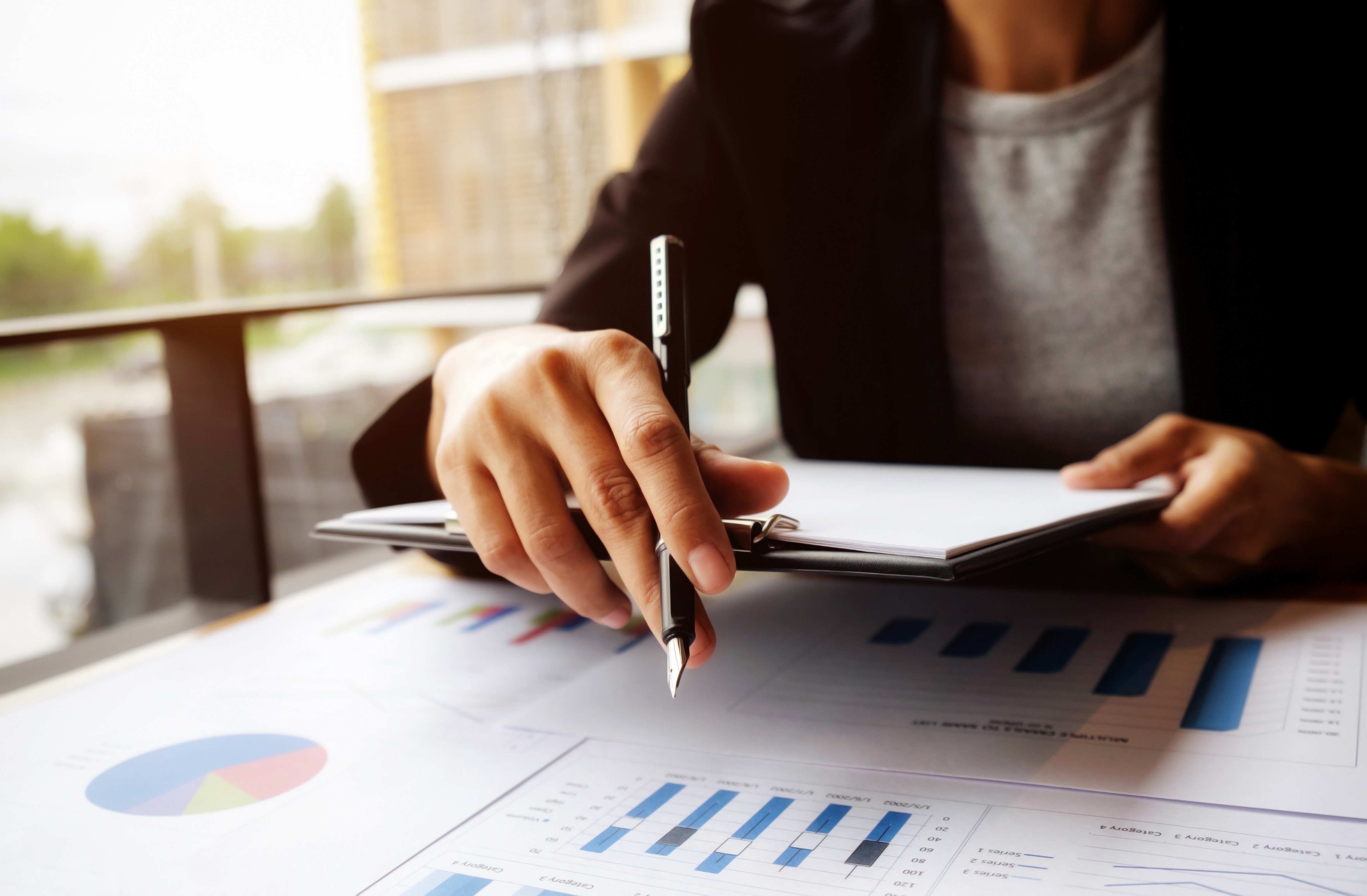 Bookkeeping professional analyzing financial reports and recording notes.