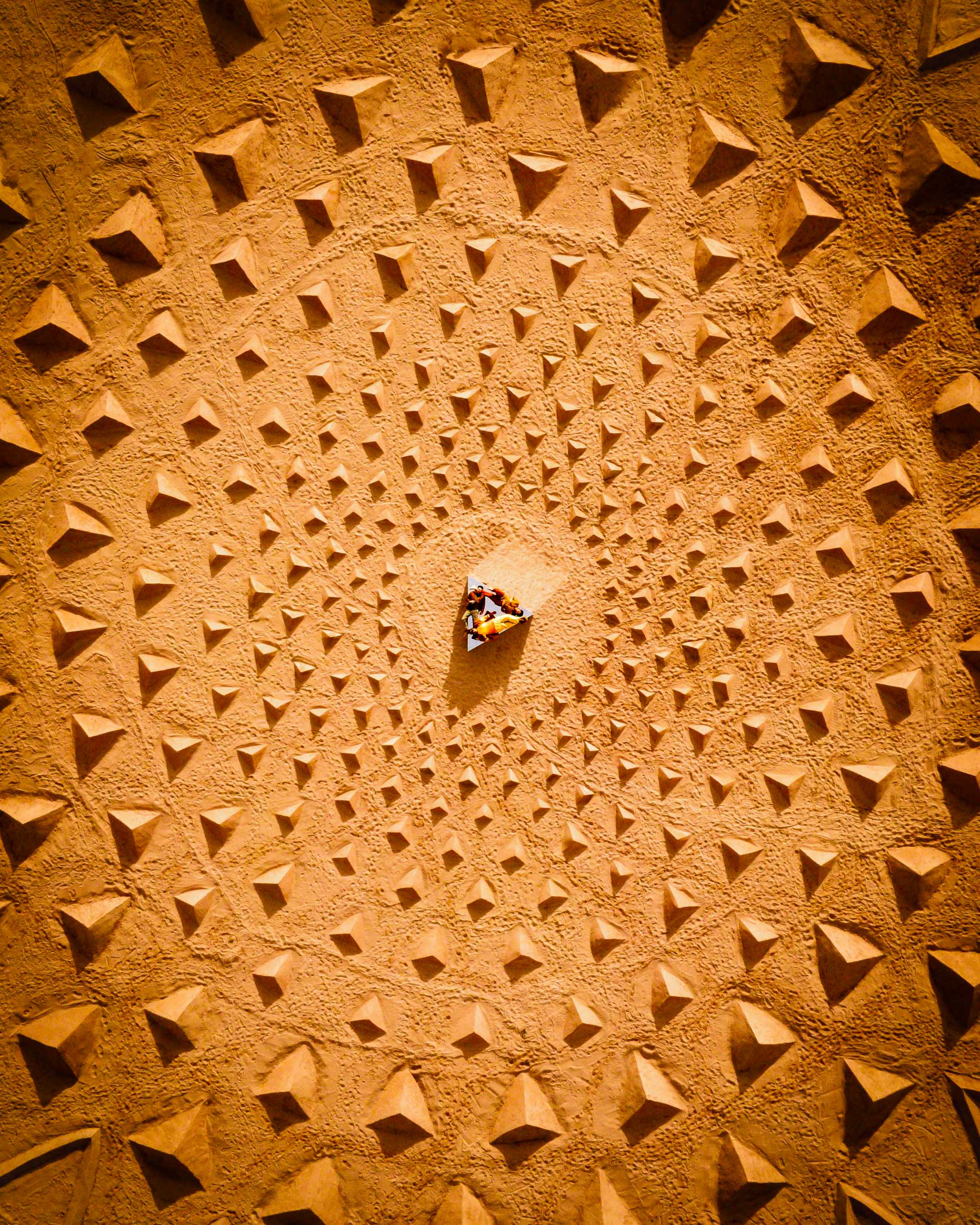 A man digging in the sand to build a massive piece of land art in a riverbed in front of Arizona red rocks