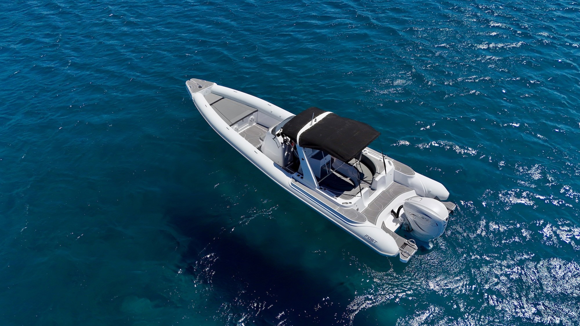 White speedboat with black canopy cruising over crystal-clear turquoise waters in the Greek islands.