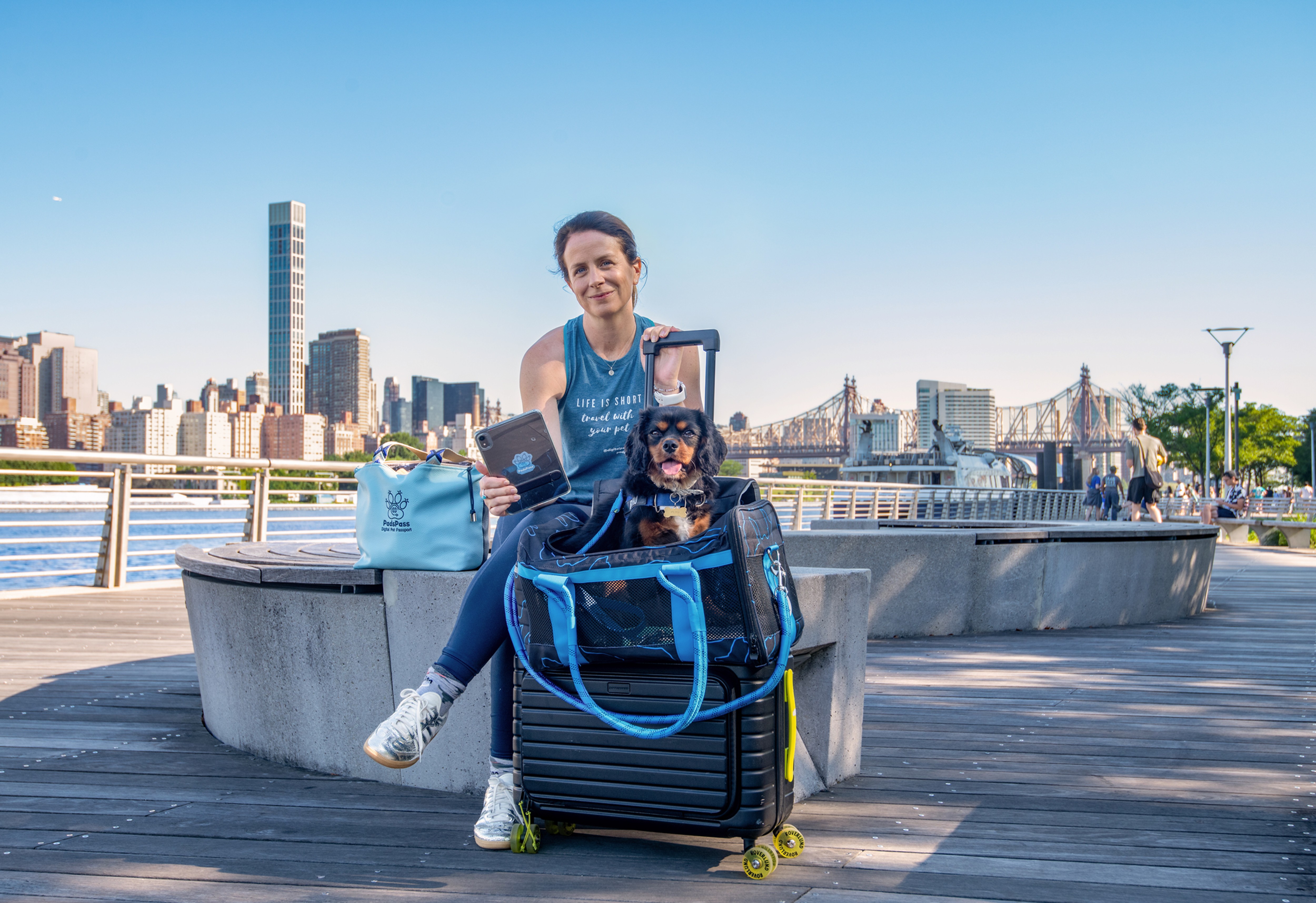 Dog inside his per carrier with his human holding a luggage ready for travel.