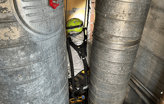 A large group photo of diverse team members gathered in an industrial-style space with arched ceiling.