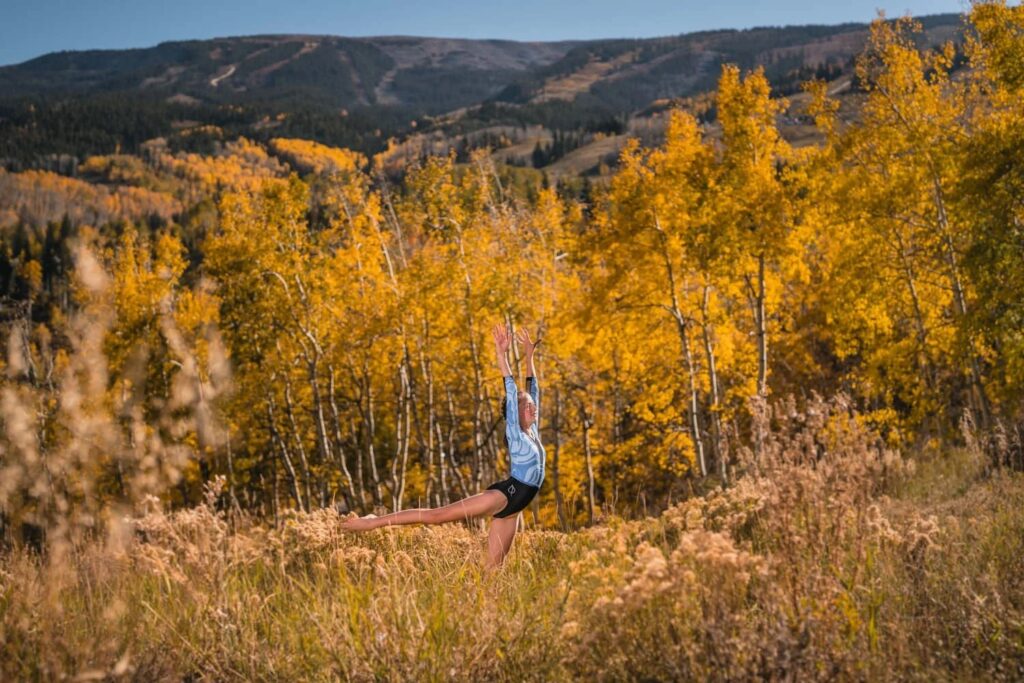 Person holding a yoga pose in an autumn meadow