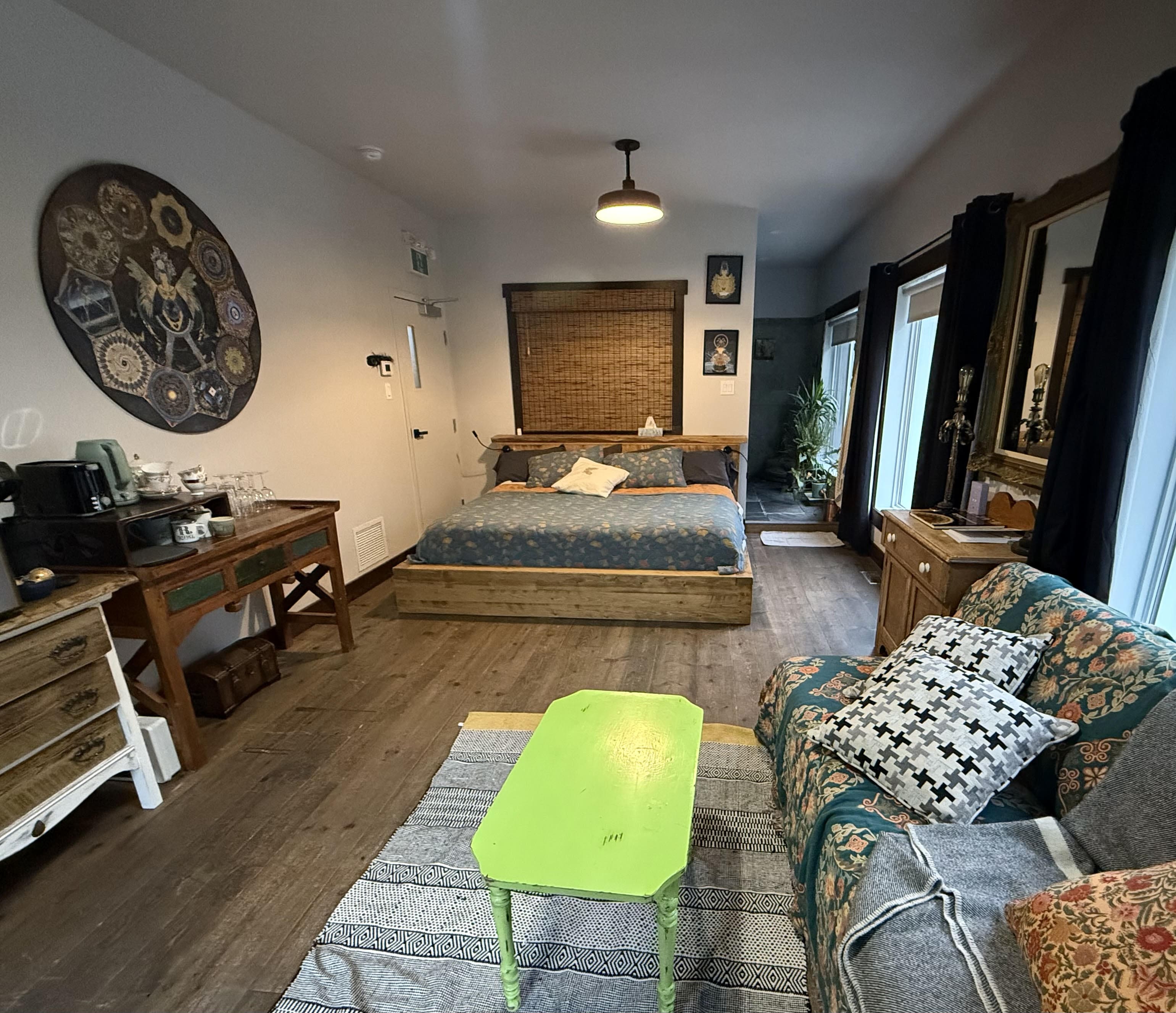 Lit en bois, déco inspirée de l’Asie et plancher de bois naturel, grandes fenêtres lumineuses.