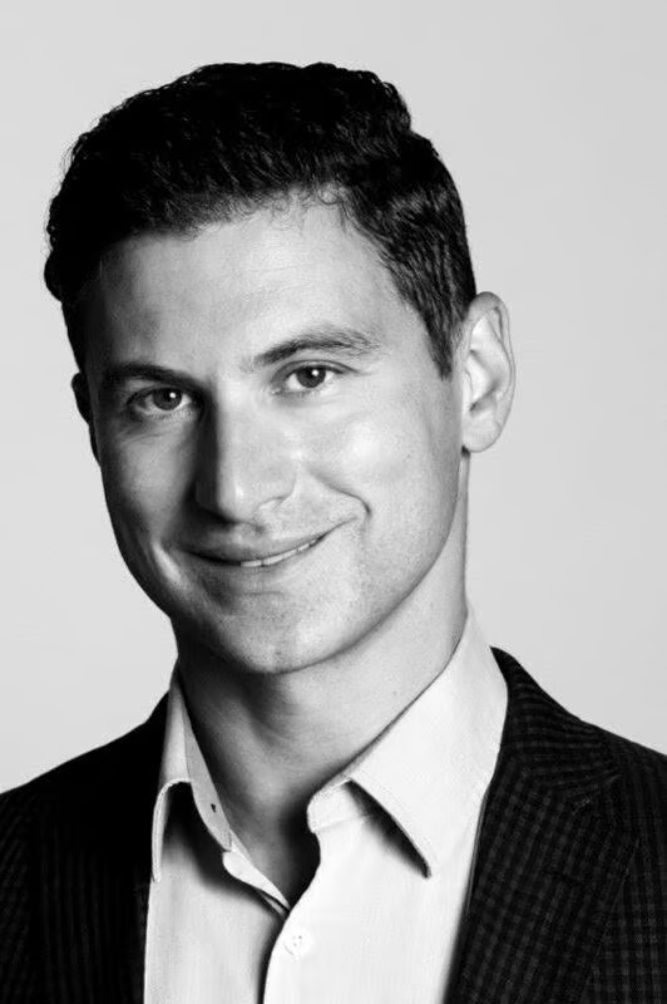 A professional black and white portrait of the founder of Kin Concierge, looking confident and approachable.