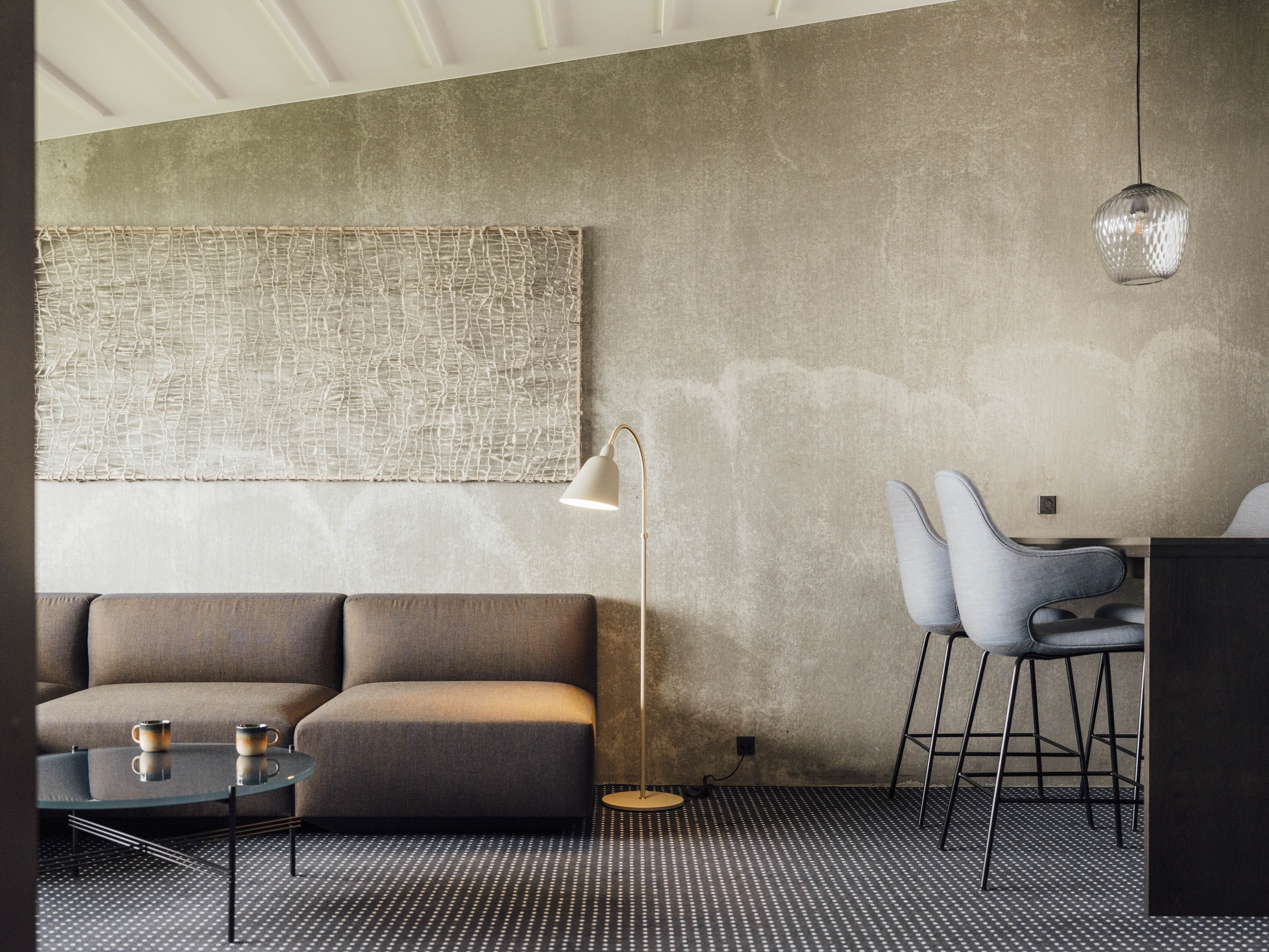a soft linen lounge chair, driftwood side table, pampas grass in ceramic vase, with the beach faintly visible through floor-to-ceiling windows