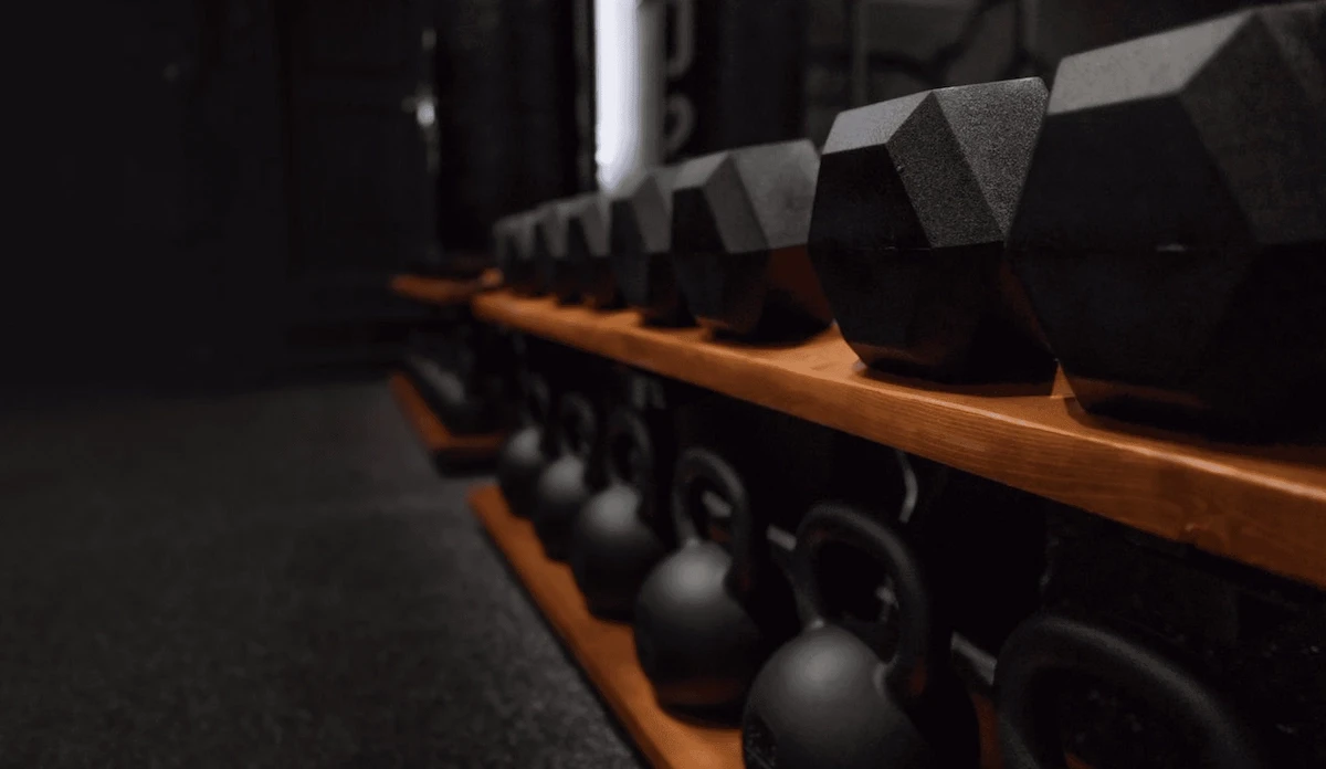 Luxury custom home gym featuring dumbbell and kettlebell storage, mirrored walls, and a heavy boxing bag, designed by Home Gym Builds in Canada.