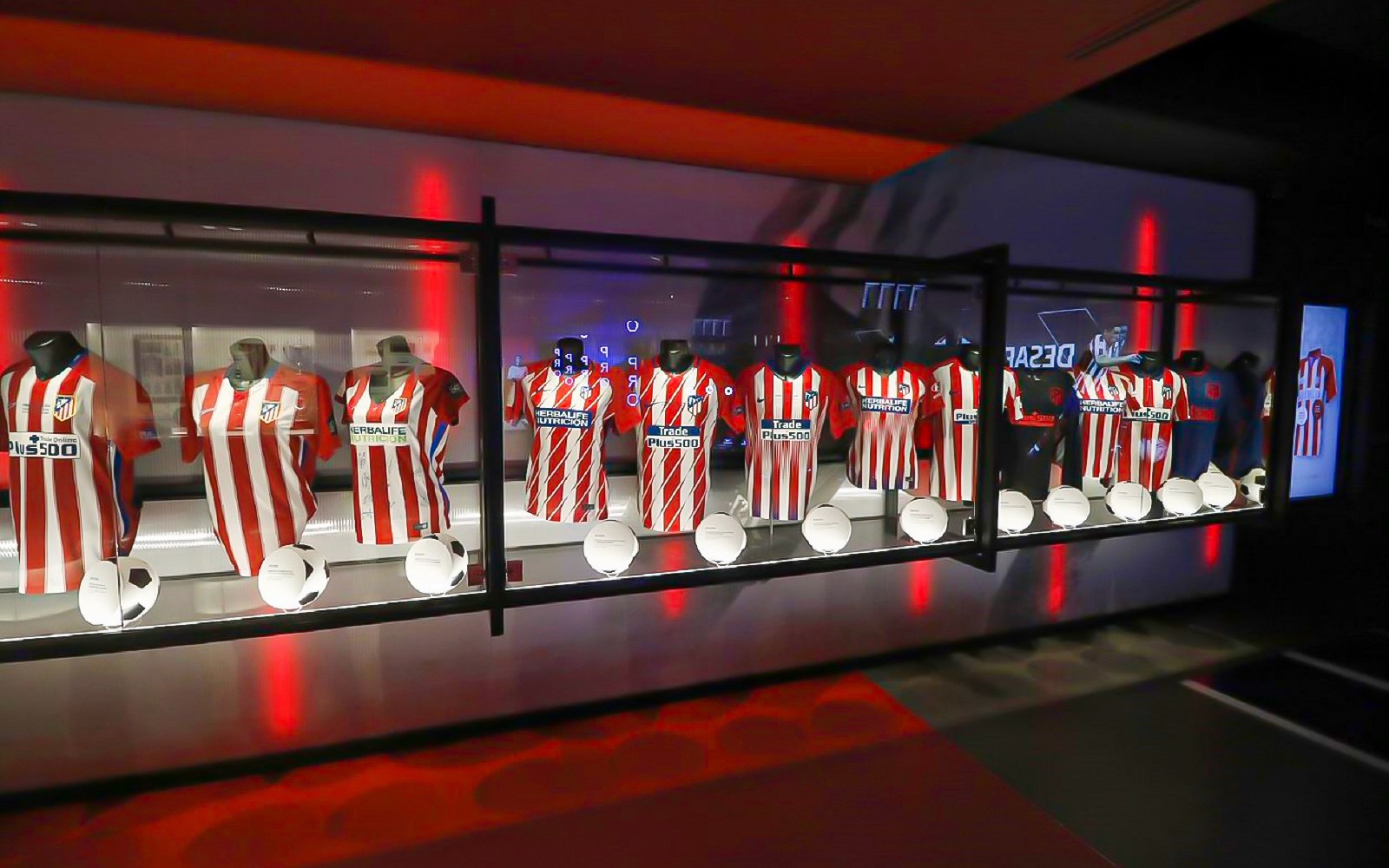 Camisas do Atlético de Madrid e bolas de futebol em exibição no Território Atleti, tour do Cívitas Metropolitano.