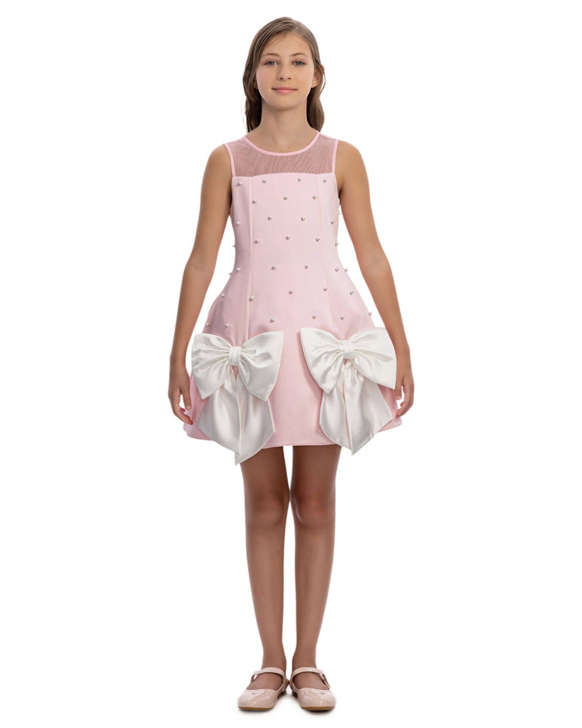 Pink dress with white bows worn by a model on a white background