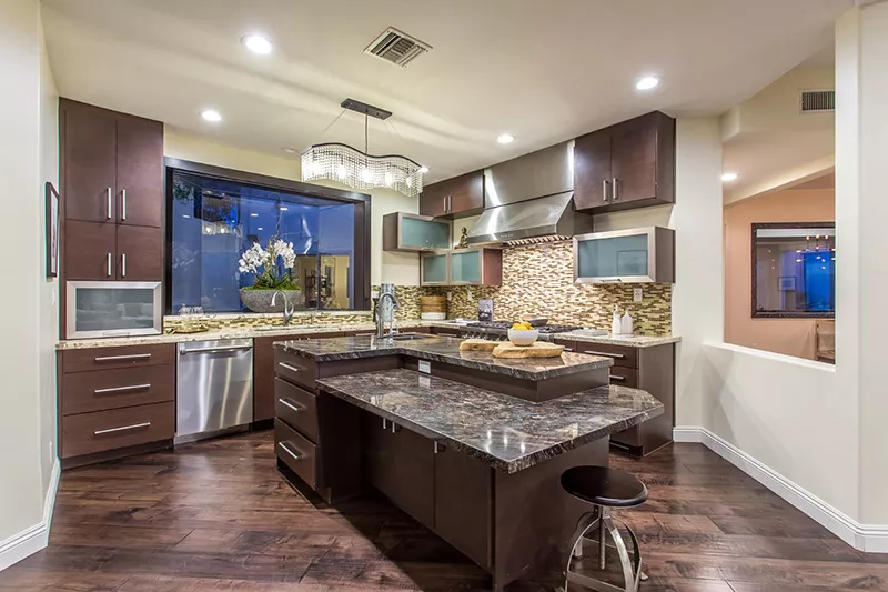 A modern white SUV is parked in a stylish driveway under a sleek carport. A woman in business attire walks towards the vehicle, conveying a professional tone.