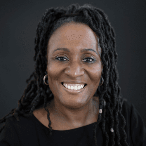Portrait of a smiling man with wavy dark hair, wearing a casual hoodie and T-shirt, photographed in soft studio lighting.