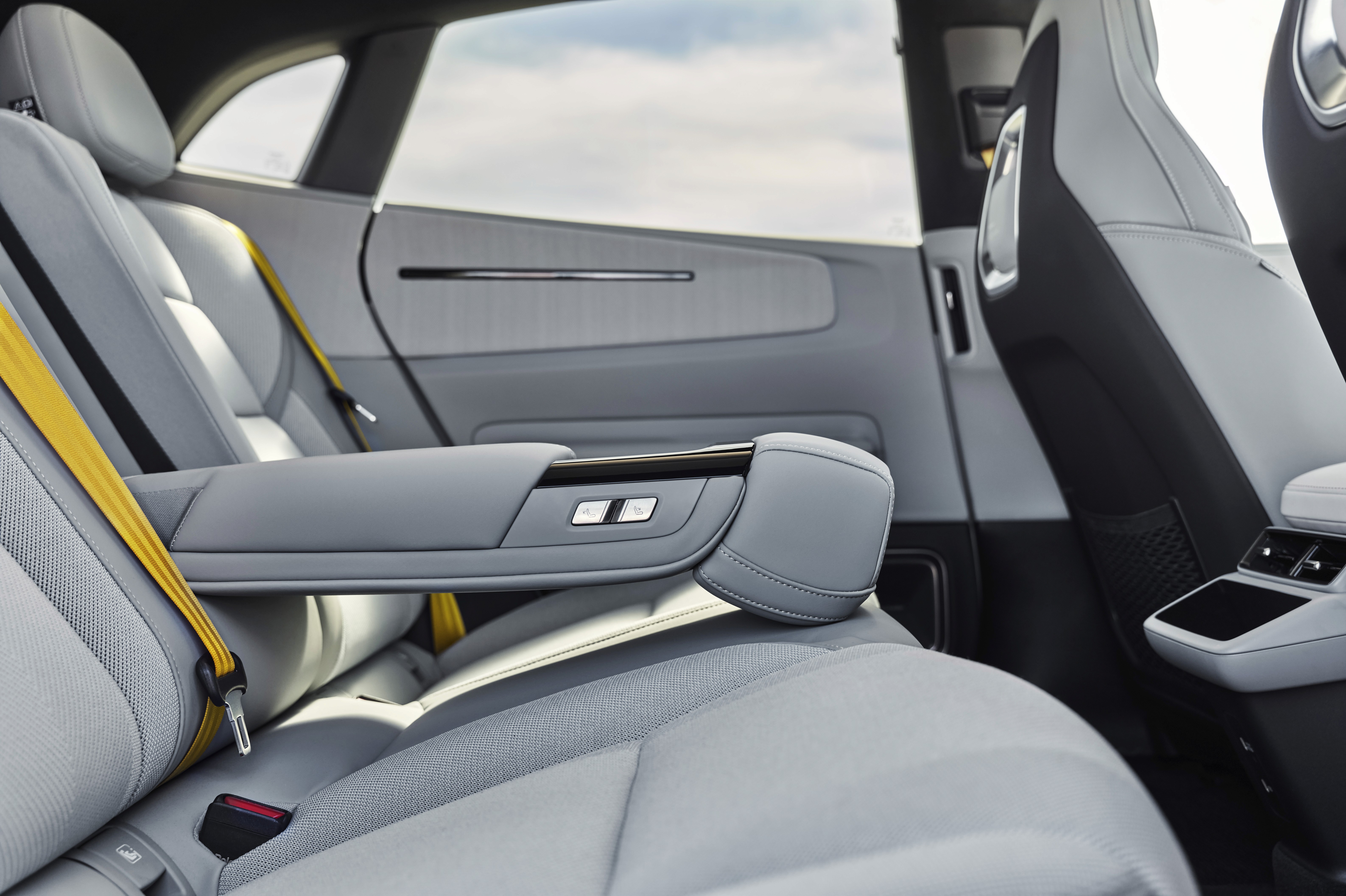 Intérieur arrière de la Polestar 4 avec sièges clairs, accoudoir central rabattable et finition premium