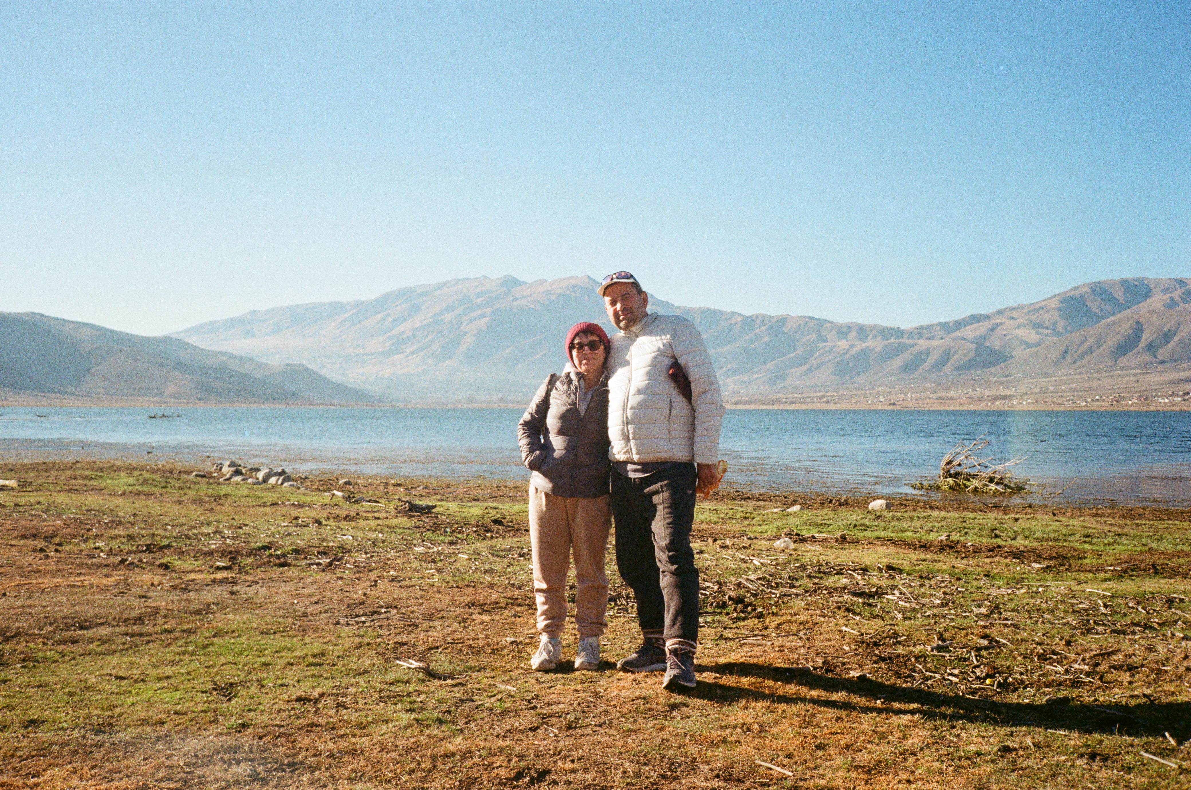 Mujer sentada sobre un tronco frente a una cascada doble en un bosque frondoso de Argentina.