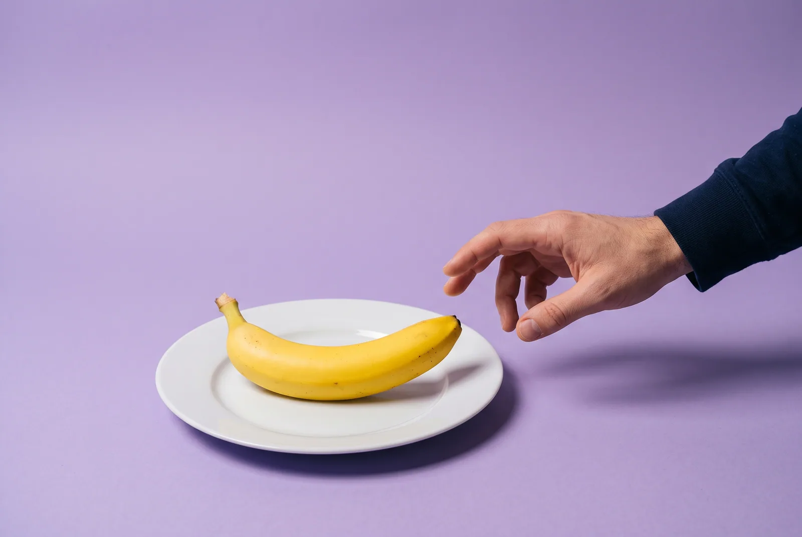 How to stop gooning: a banana under a glass cloche with a small brass key lying in front of it on a hot pink backdrop