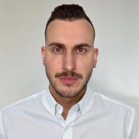 Portrait of a woman in a beige blazer with red lipstick, neutral background.