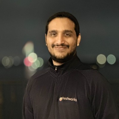 Man sitting on a red couch with hands clasped.